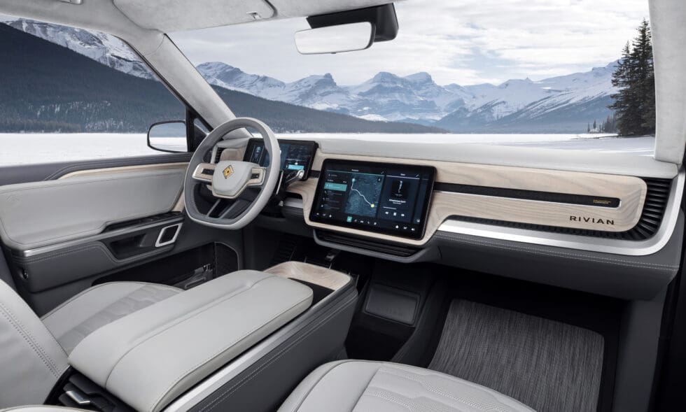 The interior of a Rivian car that is sleek and modern, light gray with wooden paneling