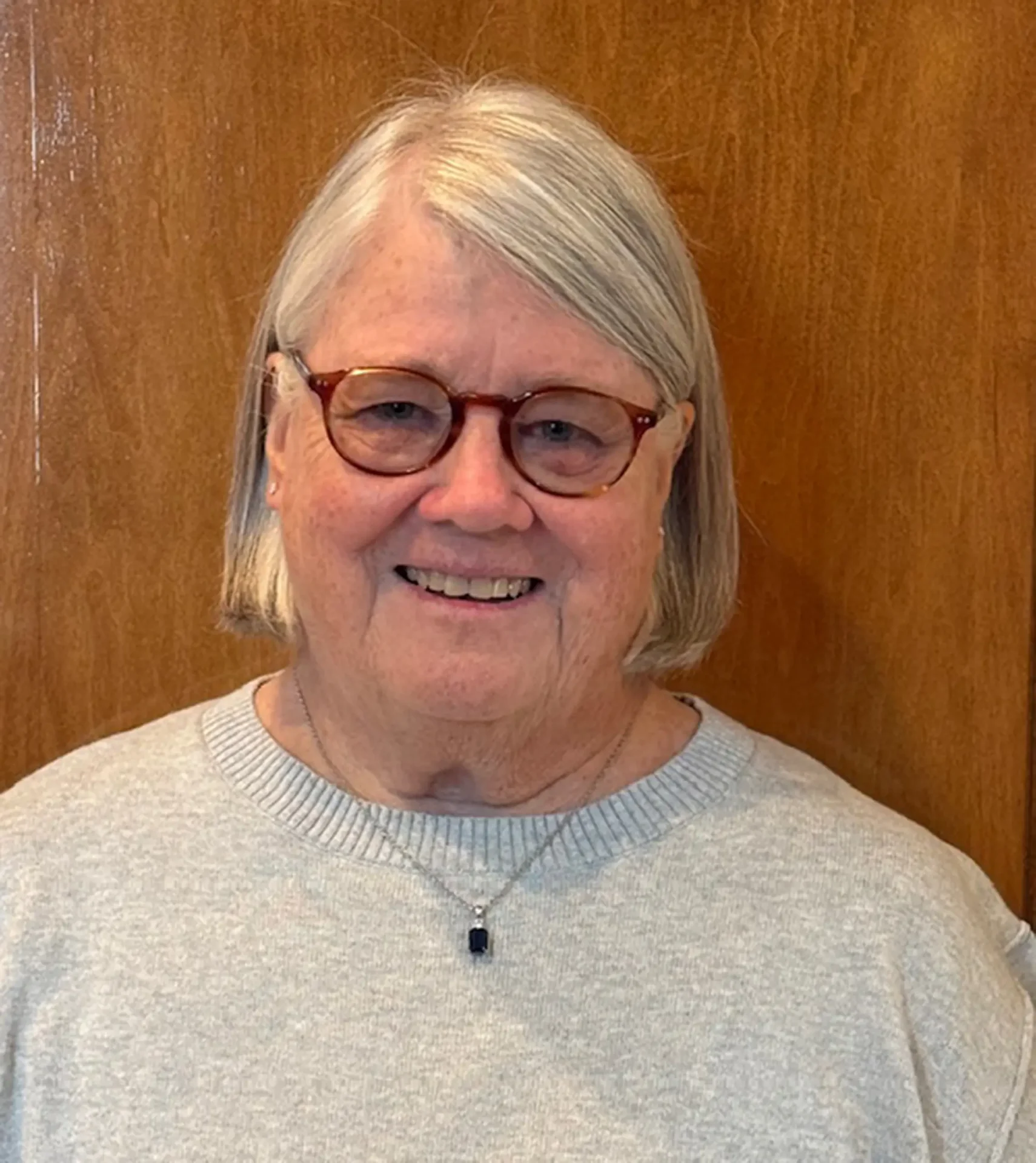 Lynn-Alandt smiling and standing in front of a wood door.
