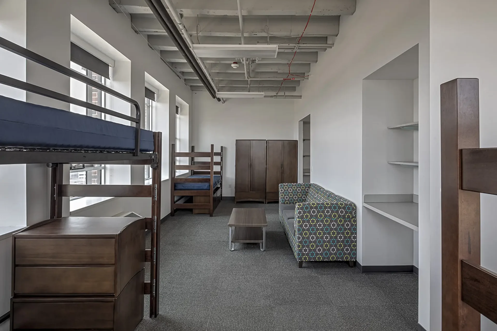 Interior shot of a dorm at the Taubman Center. There are multiple beds, a large closer and couch