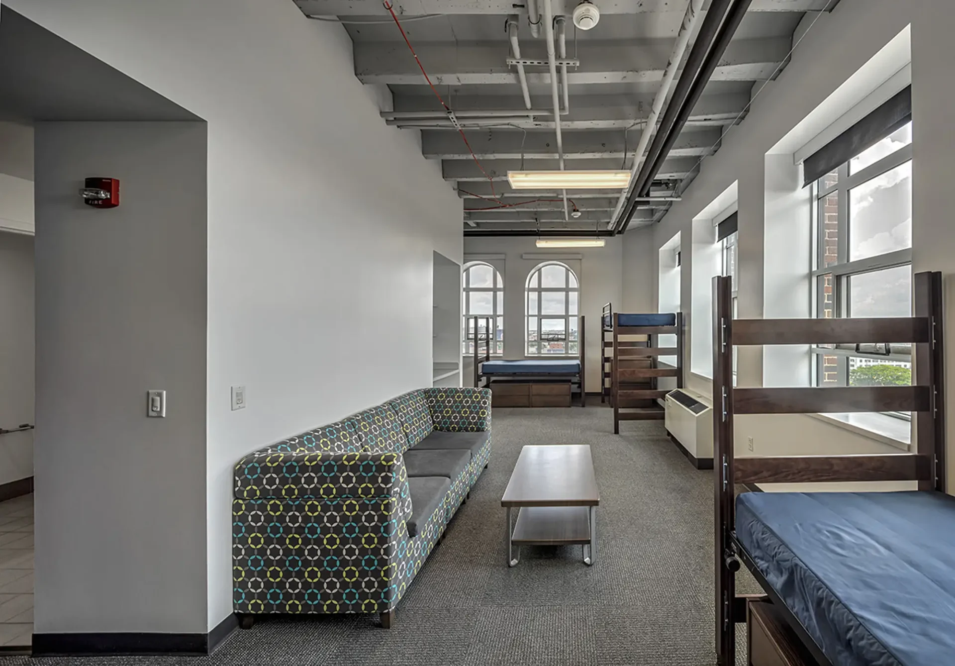 Interior shot of a dorm at the Taubman Center. There are multiple beds and a couch and large windows.