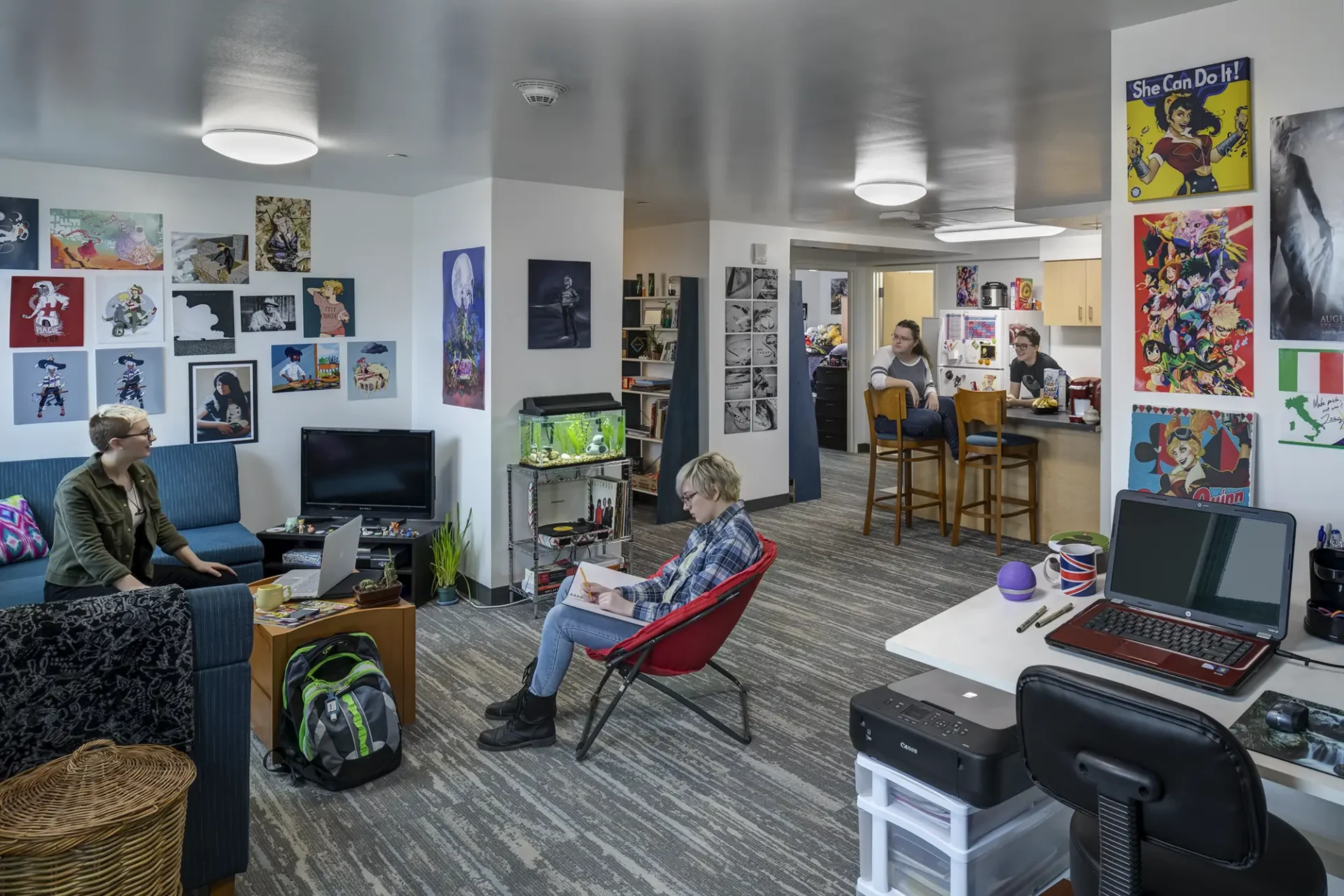 Students lounging and working in a large open space. Posters and artwork decorate the walls and spaces making the room very colorful and welcoming