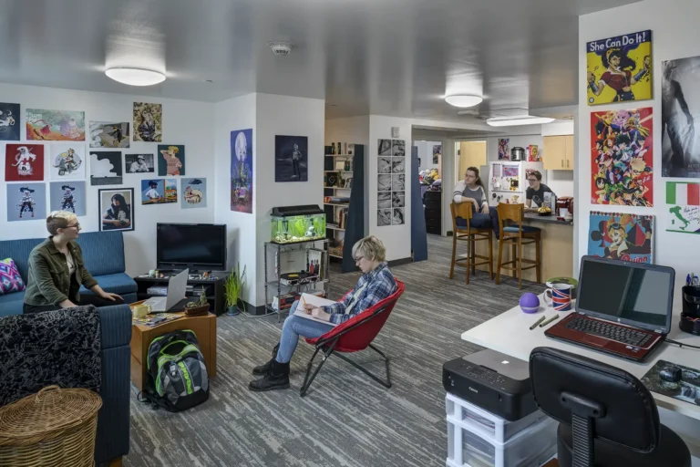 Students lounging and working in a large open space. Posters and artwork decorate the walls and spaces making the room very colorful and welcoming