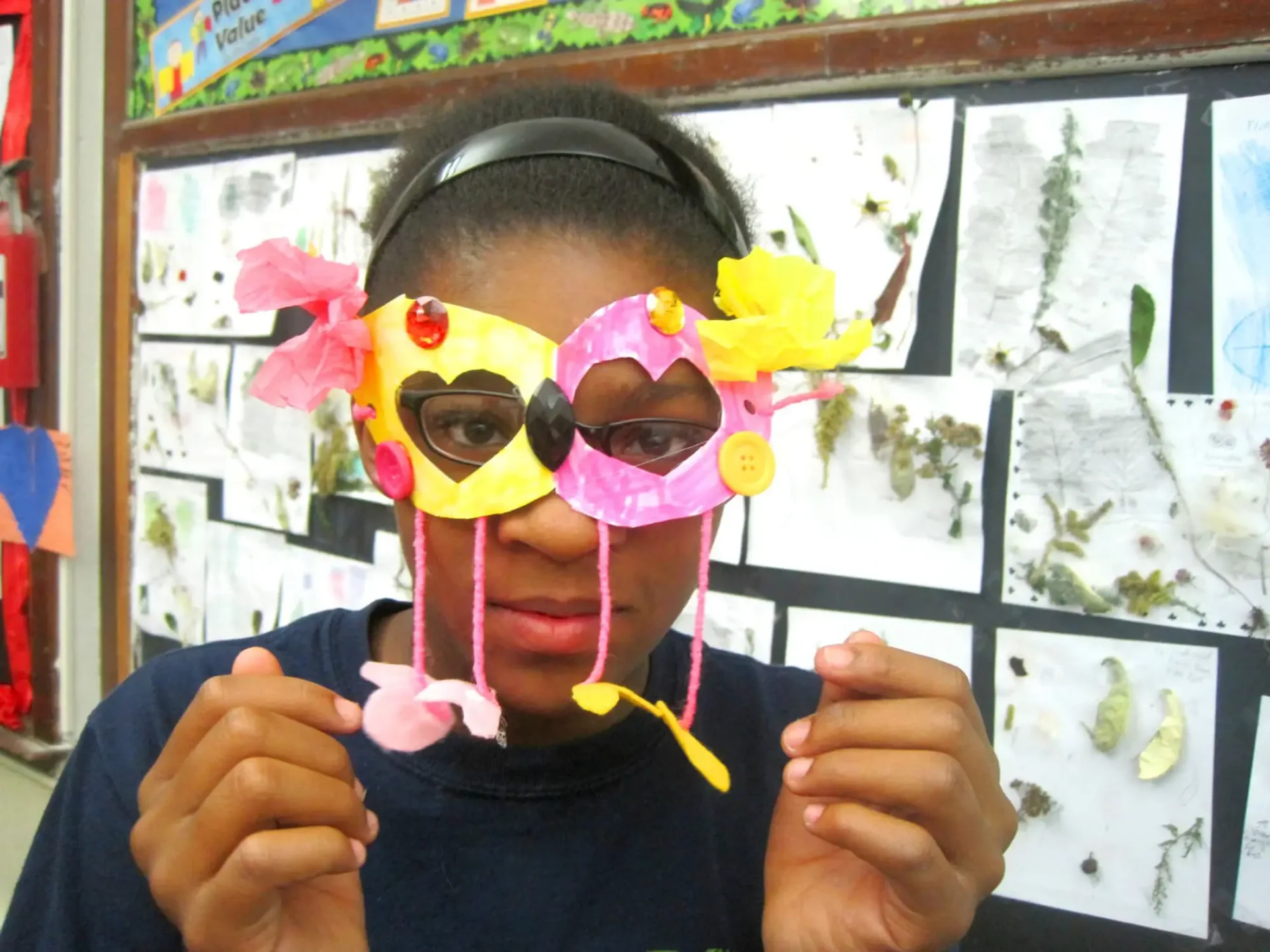 A young girl holding up a paper of paper glasses over her eyes