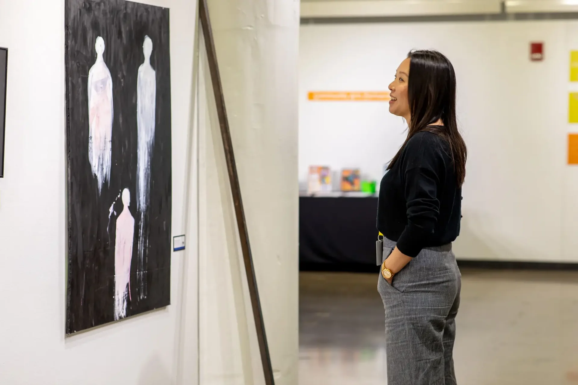A woman admiring a large piece of artwork and smiling