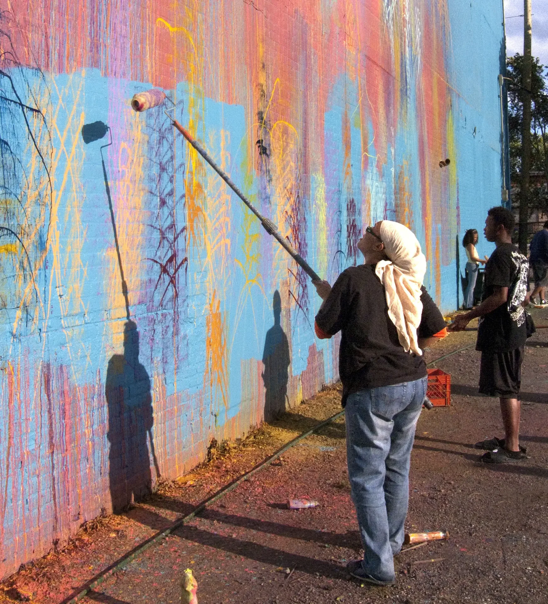 A woman painting a brick wall with a paint roller