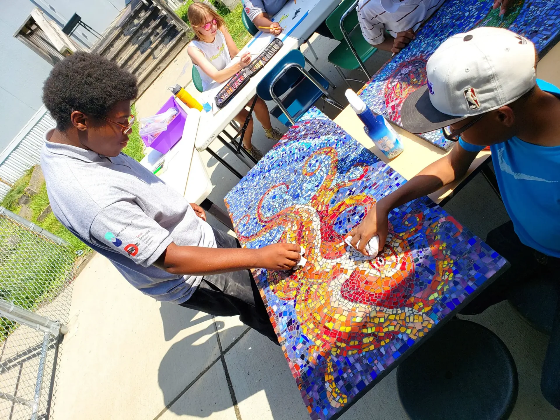 Two kids working on a mosaic outside
