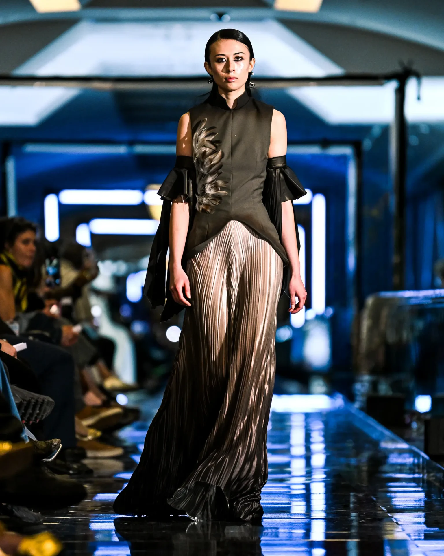 Model wearing a sleeveless shirt with feathers and leather arm cuffs