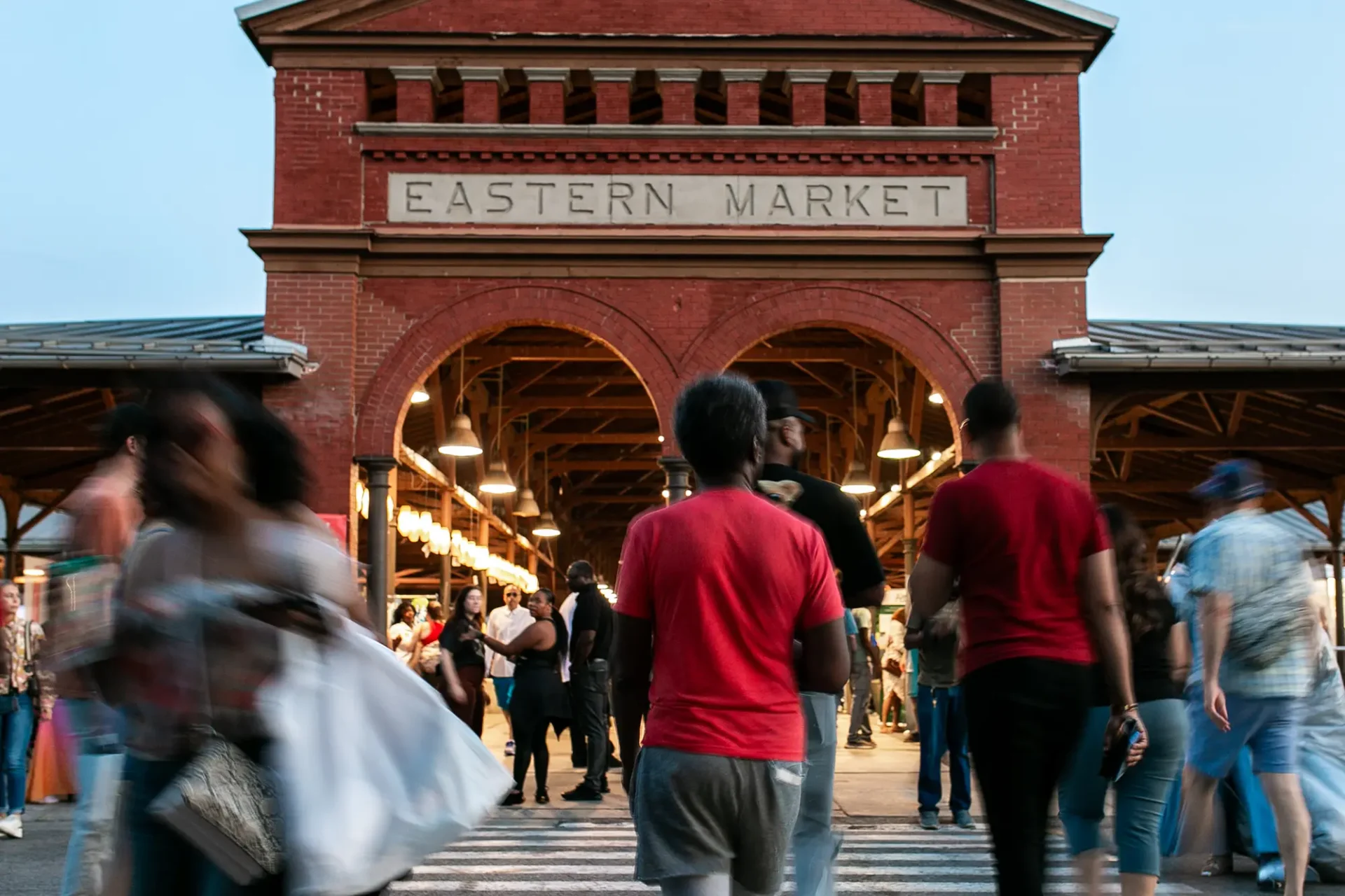People walking into the Eastern Market shed in the evening
