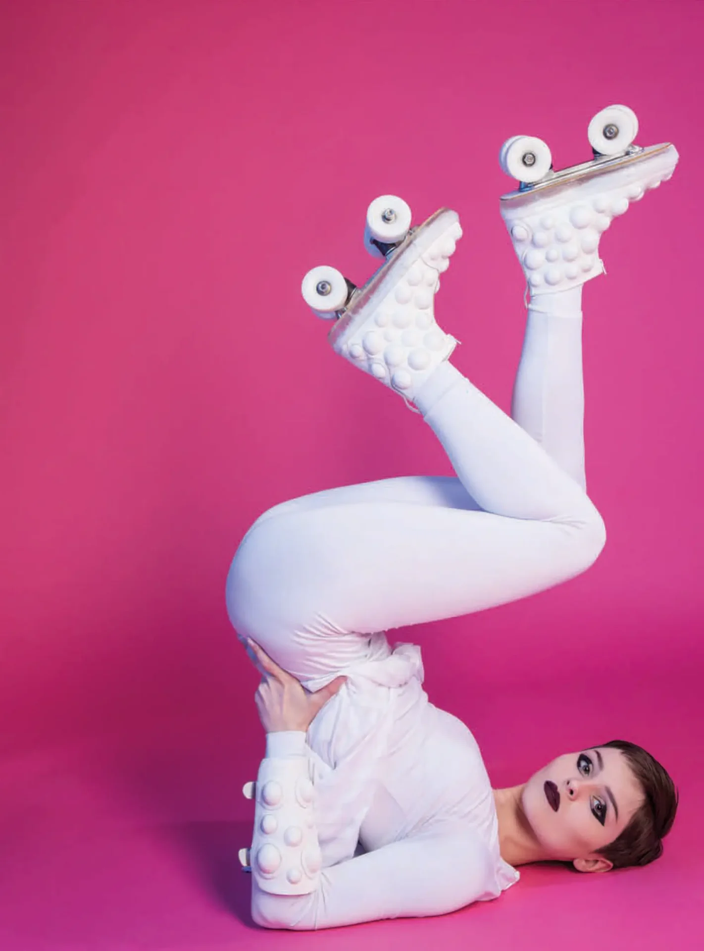 A woman wearing Bubble roller skates created from recycled and sustainable materials. She is on her back with her feet extended up into the air to show off the skates