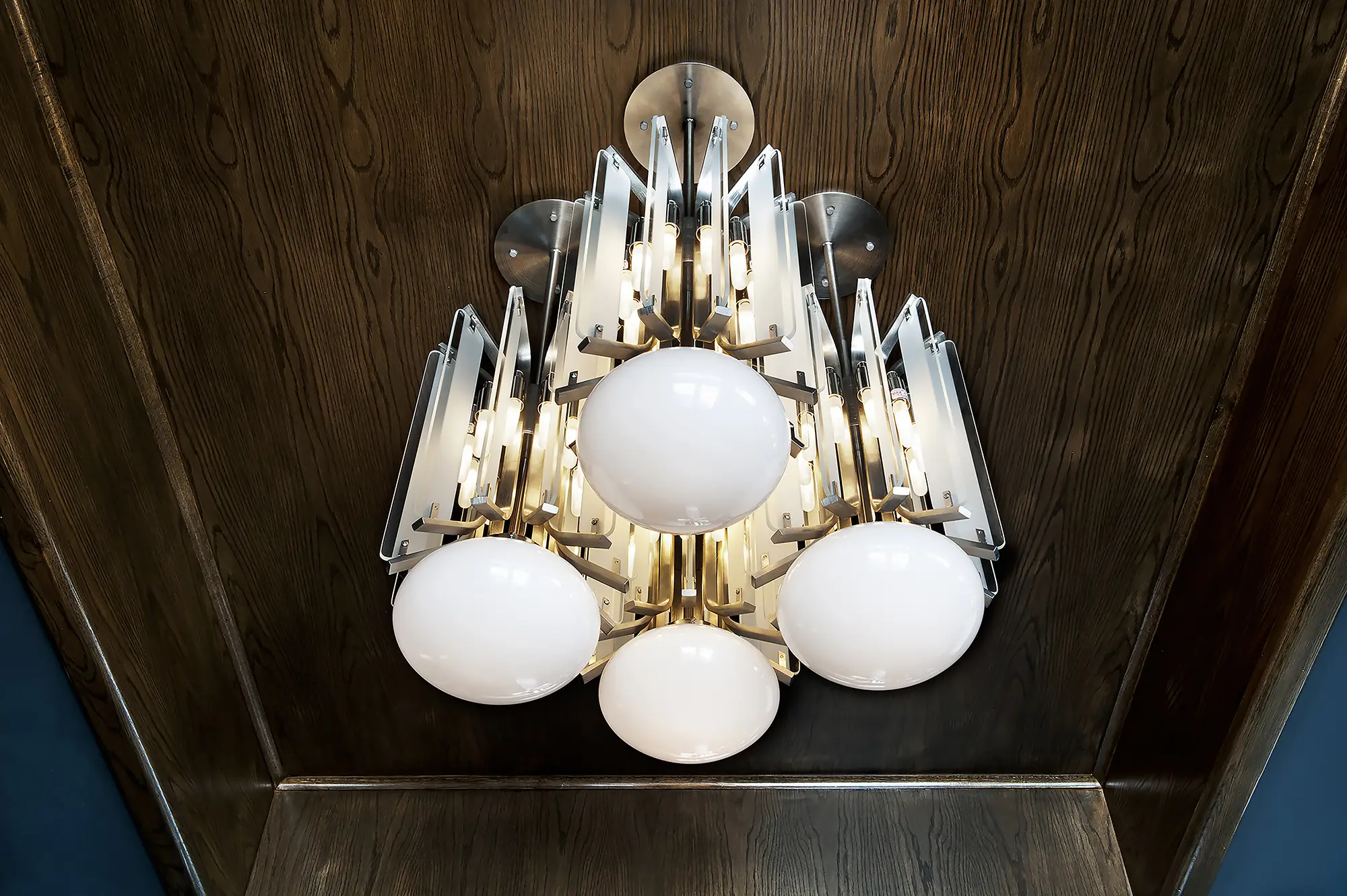 A chandelier, adorned with glass panels and 4 large bulbs, hanging from a wood ceiling in a room