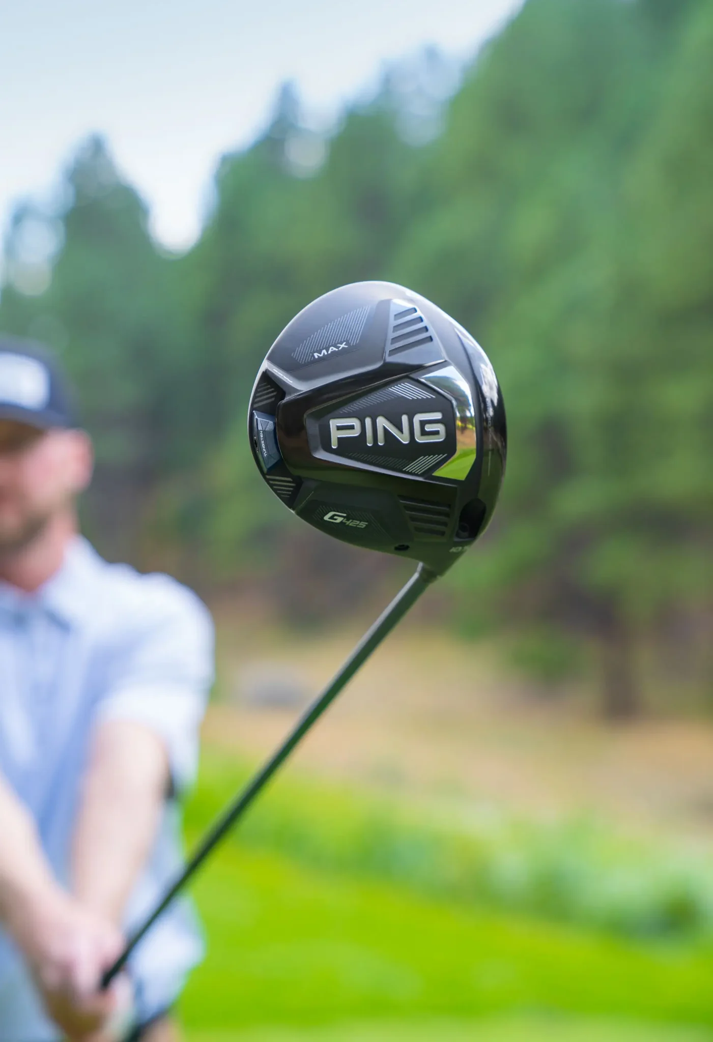 A person holding out a PING G425 driver on a golf course