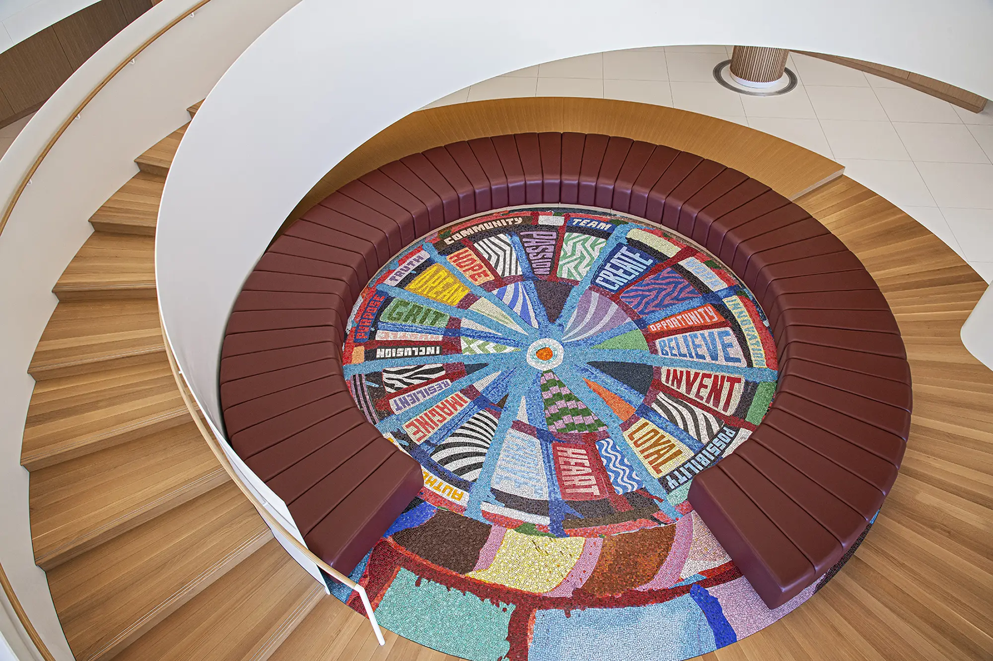 A spiral staircase leading down to a pit seating area with a colorful carpet on the ground