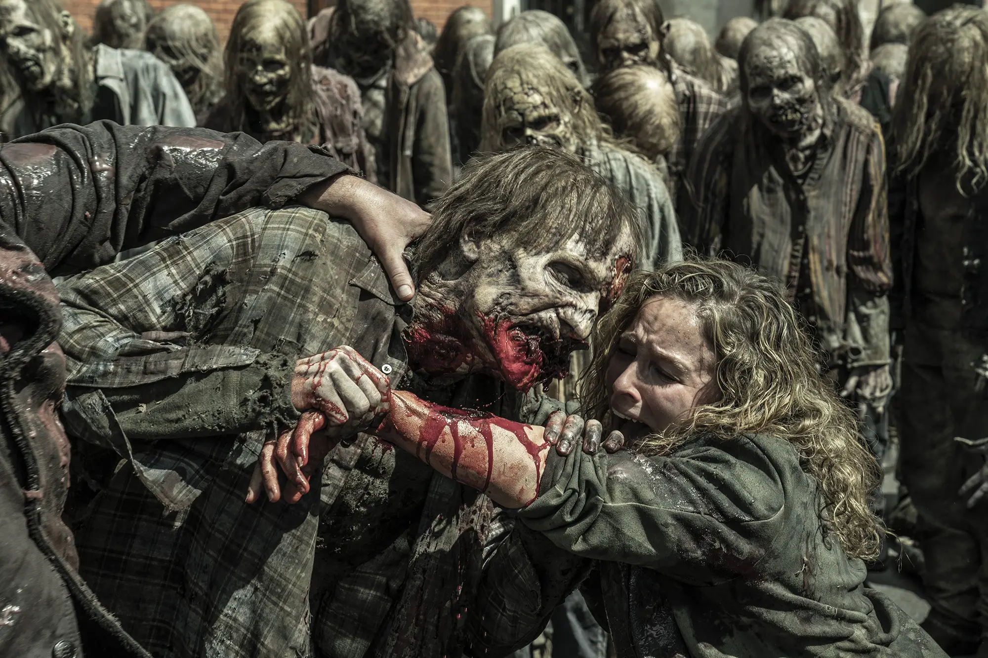 A zombie biting a woman's arm surrounded by other zombies