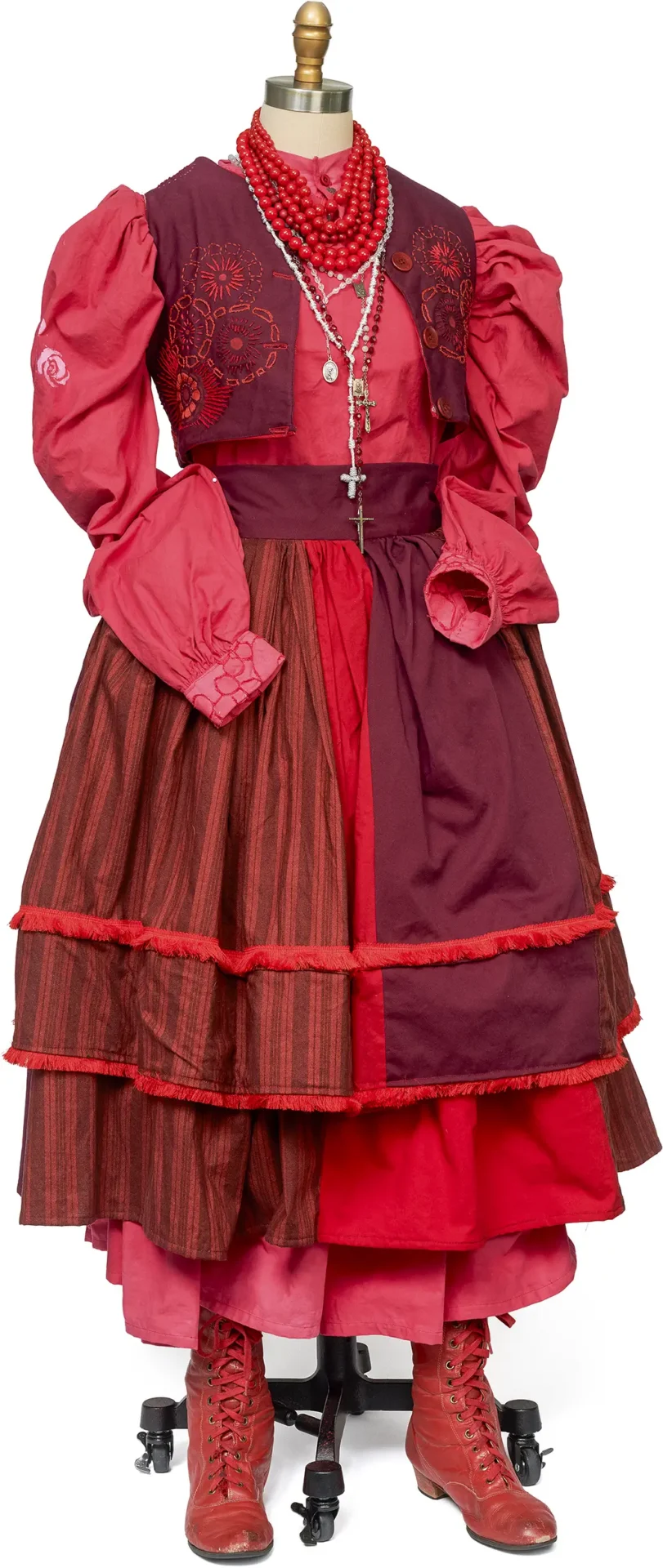 Traditional Polish garment on a dressform in shades of red with found boots.