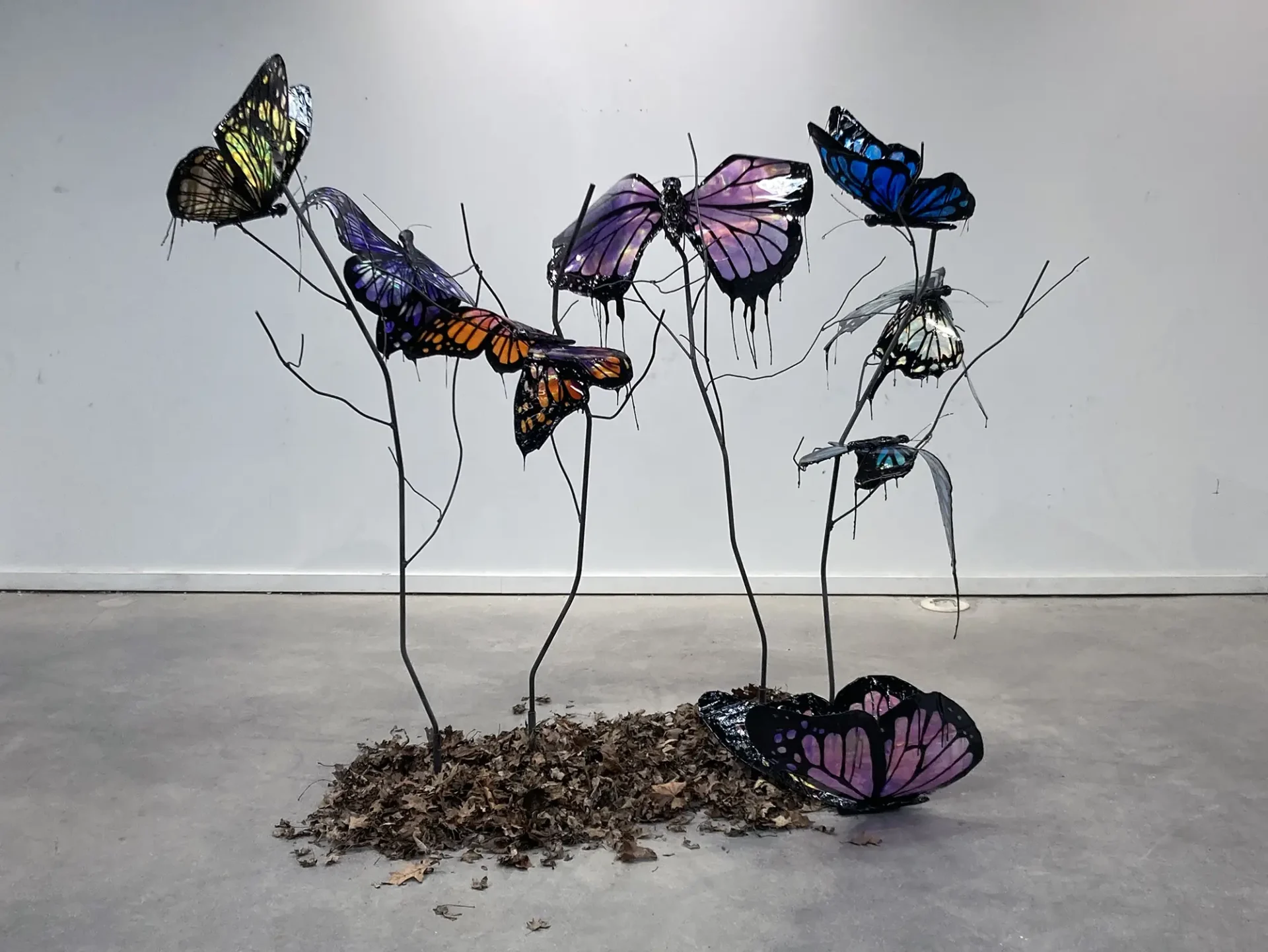 Oversized butterfly sculptures "melting" on branches made of steel rods.