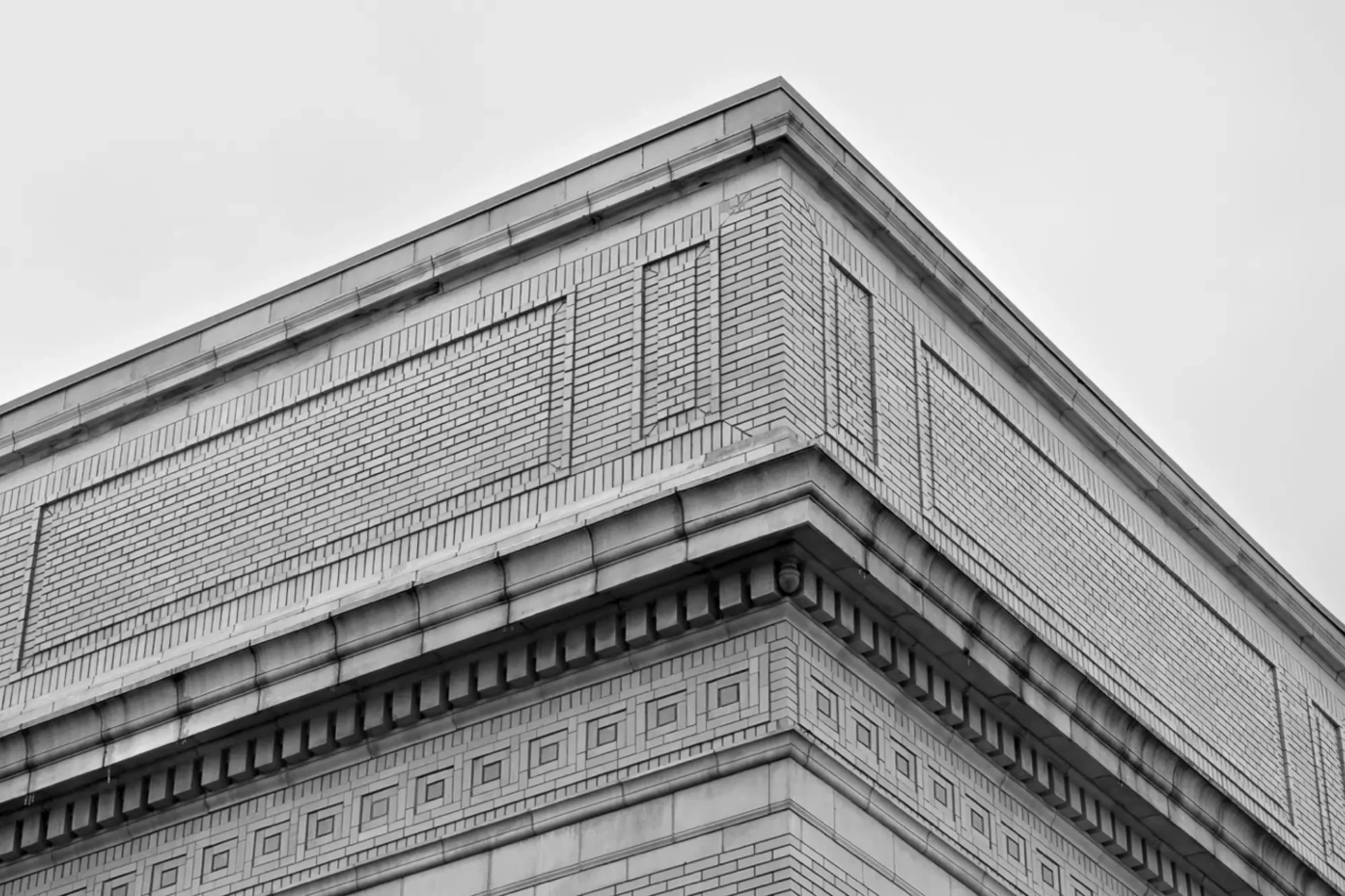 B&W photo looking up to corner of decorative building with an empty sky