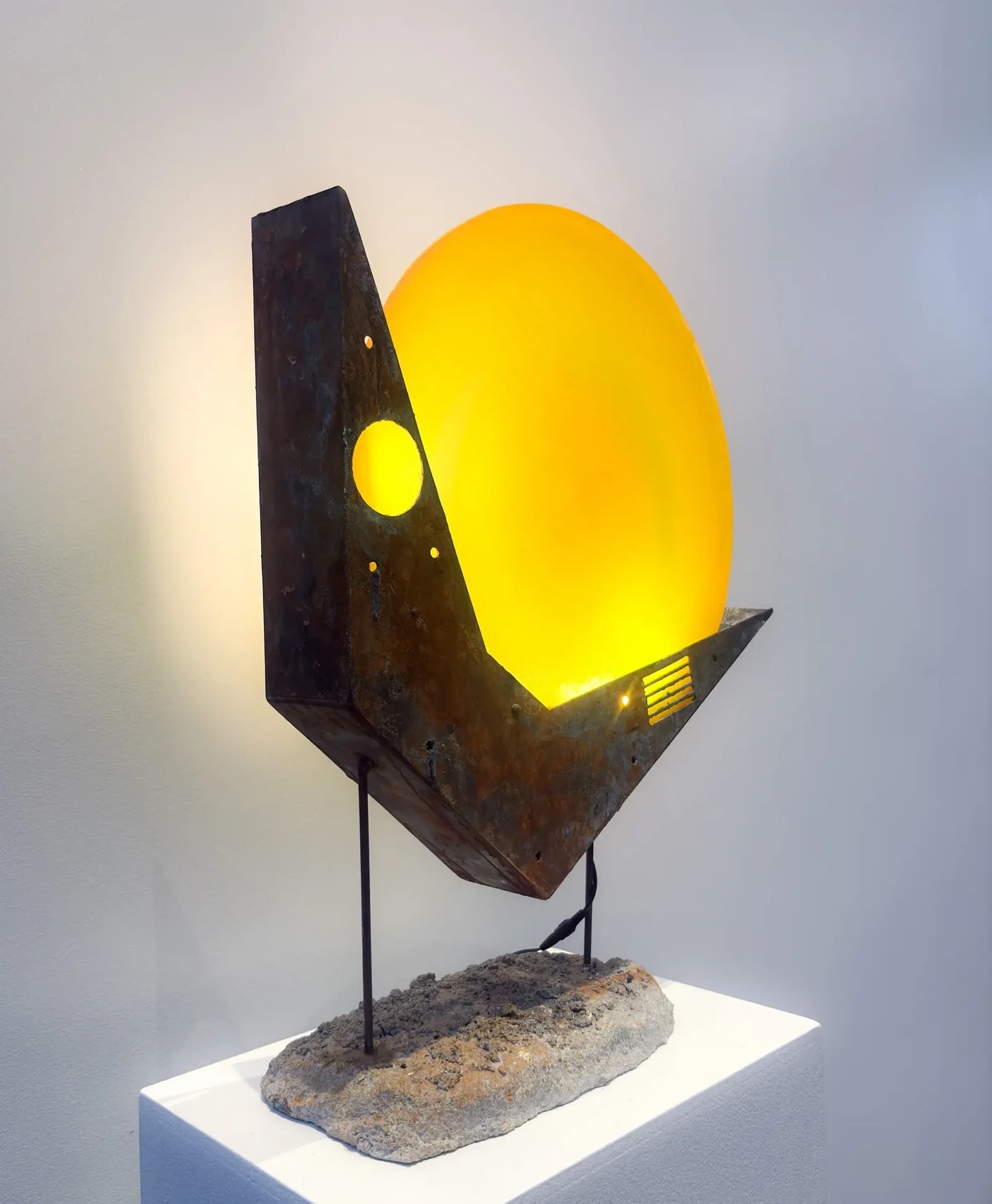 Yellow glass disc lamp in a steel and concrete base on a pedestal
