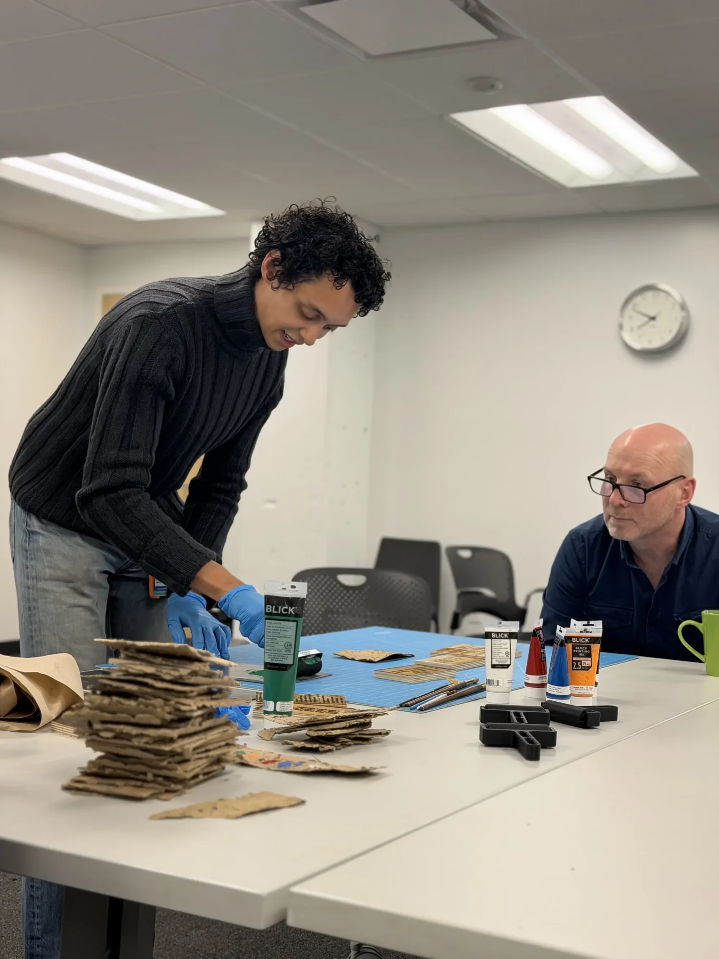 A student showing their process work to someone at the table