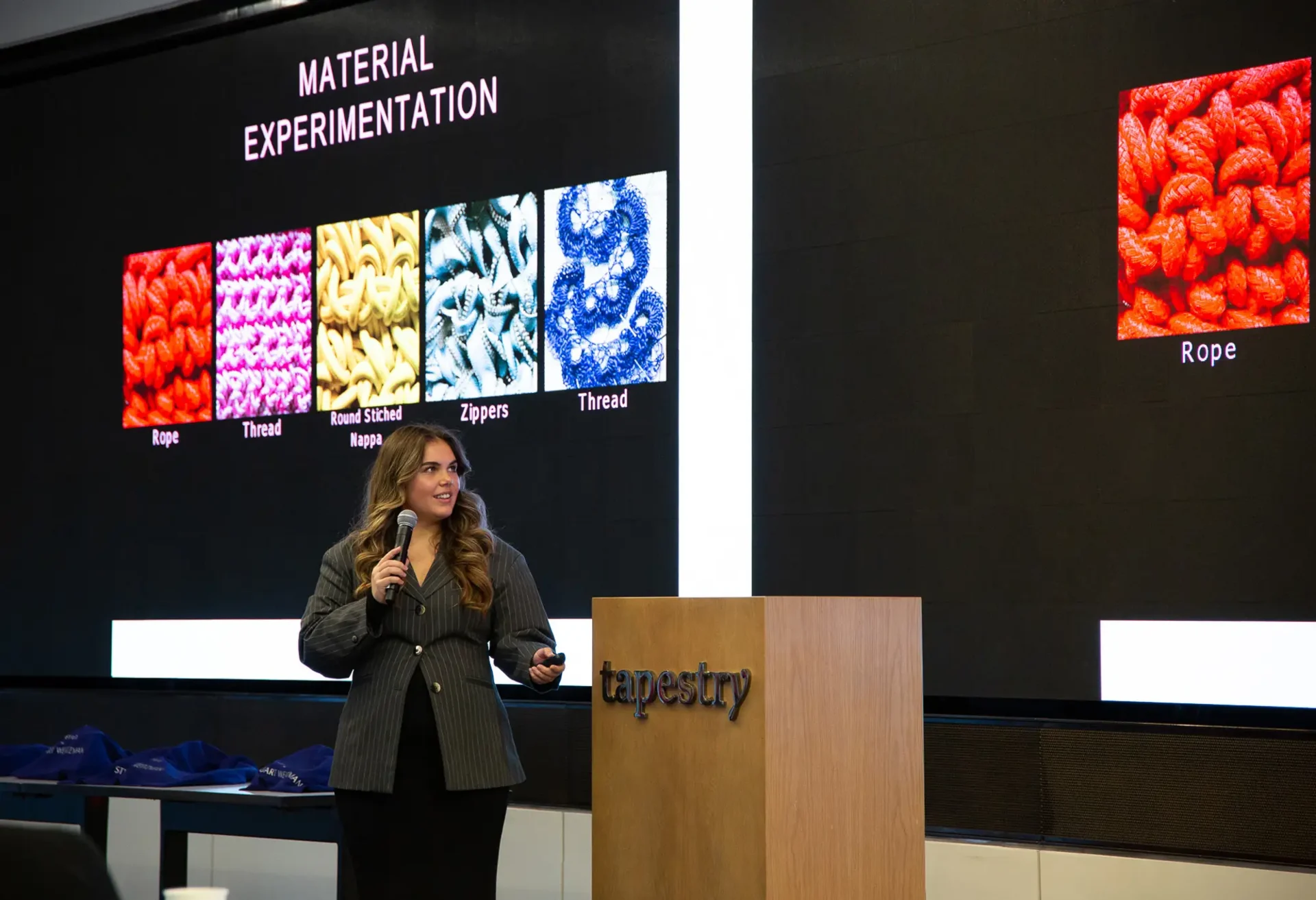 A student presenting work in front of a podium that says 'tapestry'