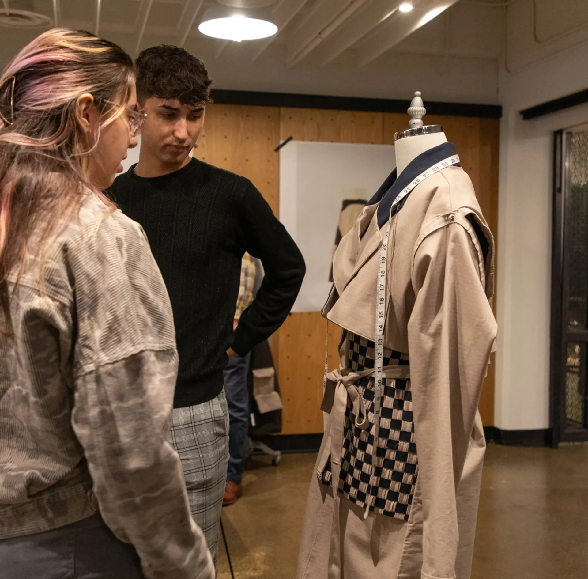 2 students reviewing a jacket on a mannequin bust
