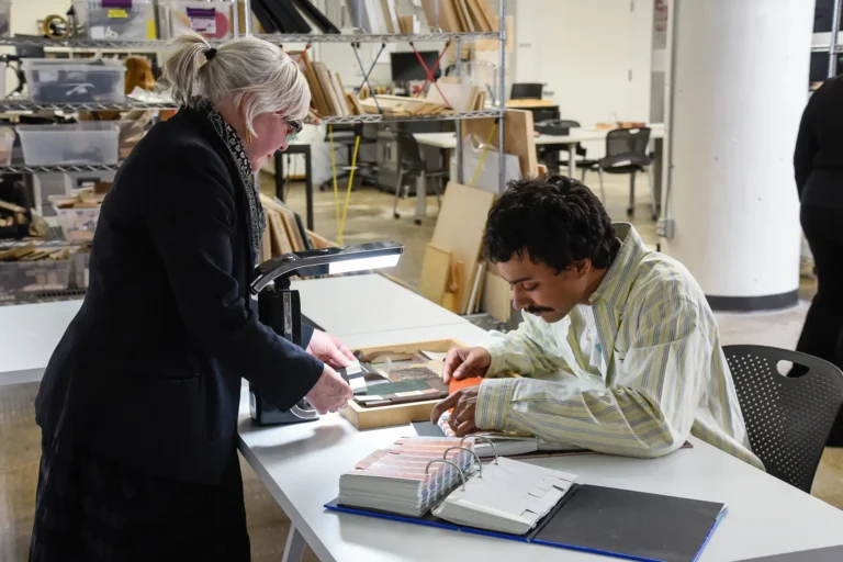 A faculty member helping a student pick color samples at a table