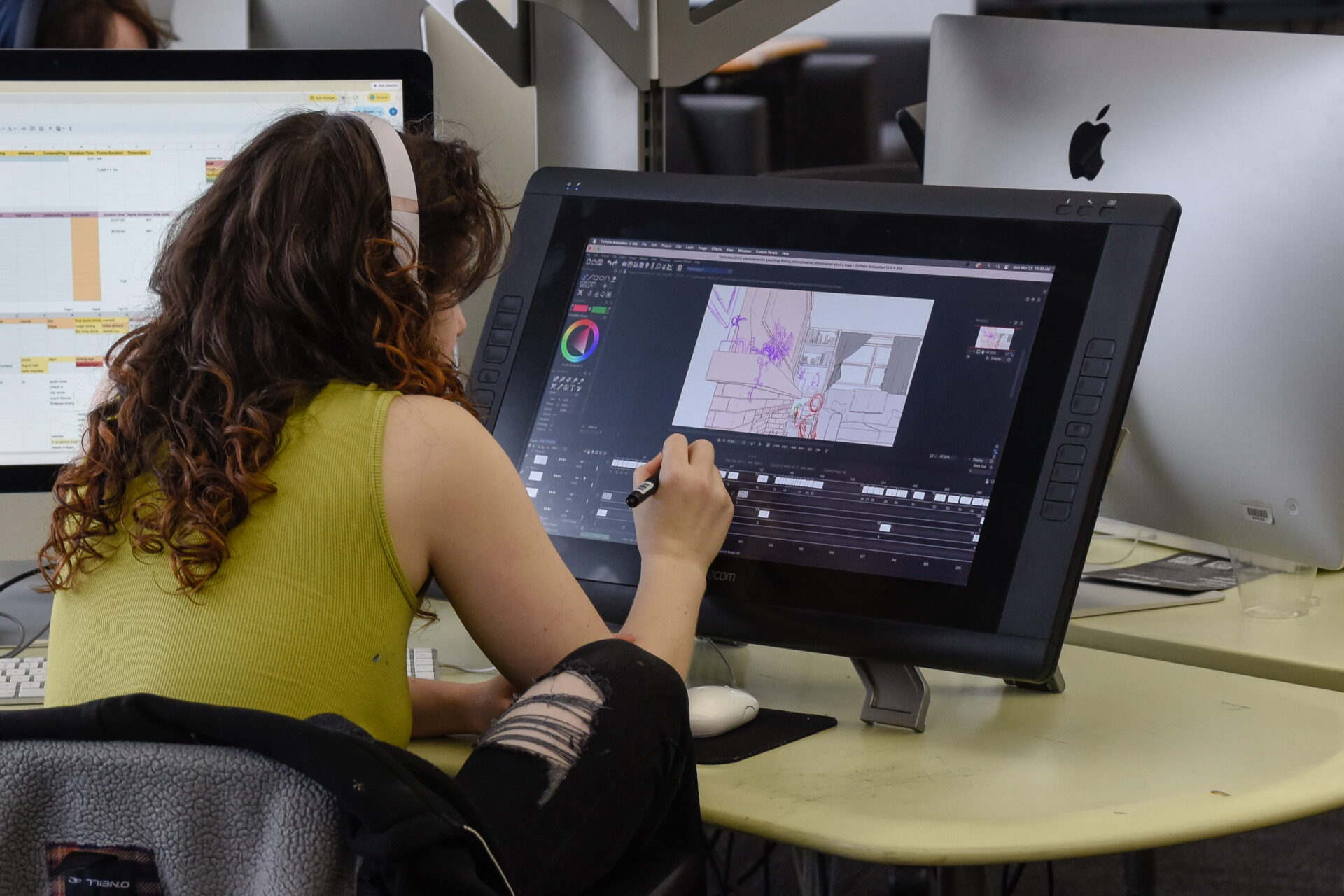 A student in a green shirt sketches on a Wacom Tablet in a Concept Design studio.