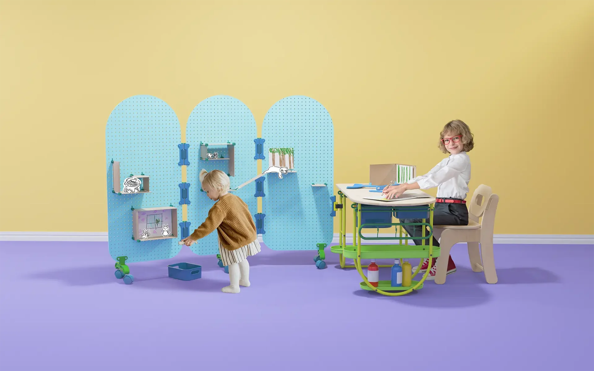 Whole view of Children's Toy with pegboard walls and desk with two children interacting with toy.