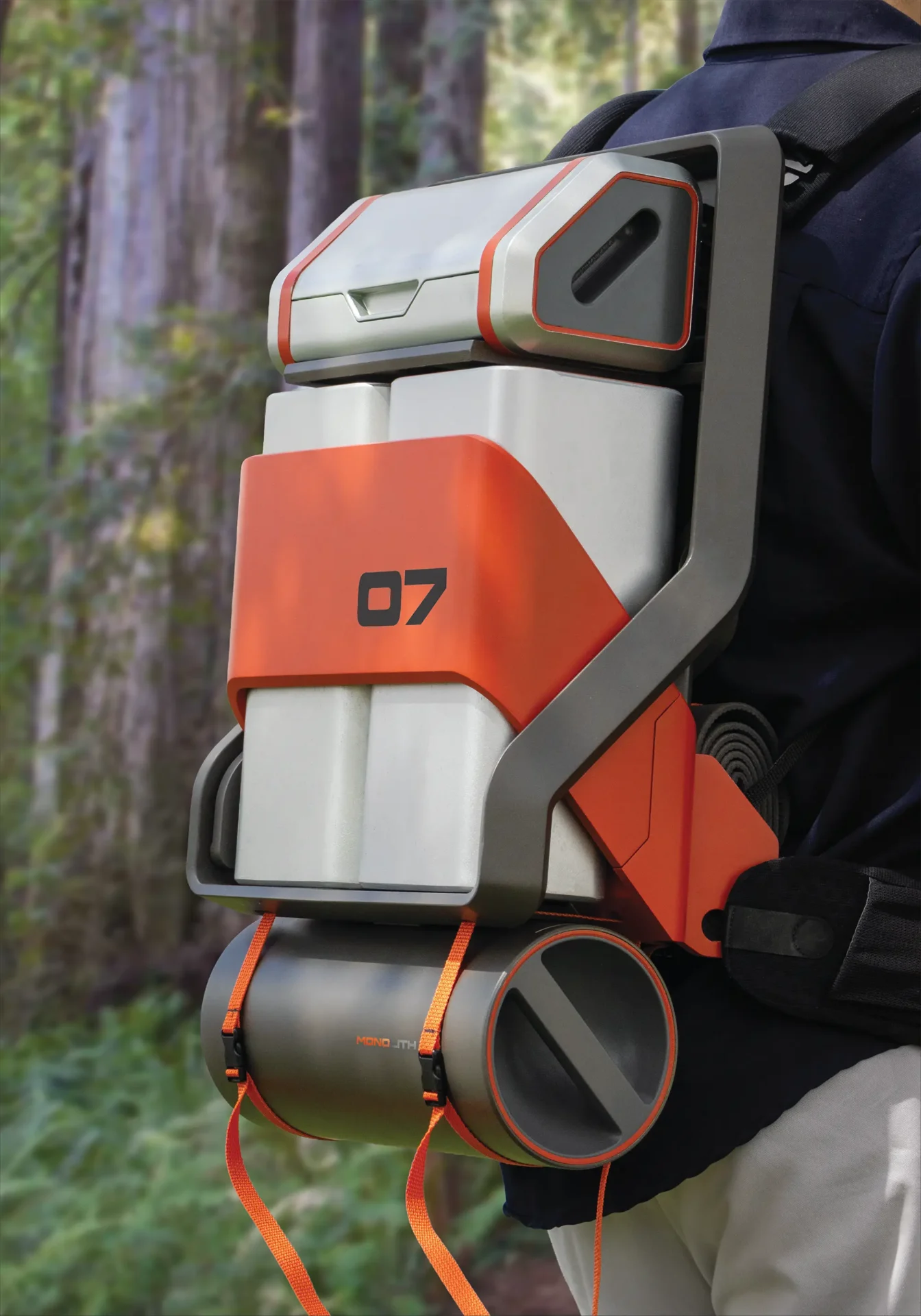 Rendering of orange and grey and black Backpack on a model with woods in the background