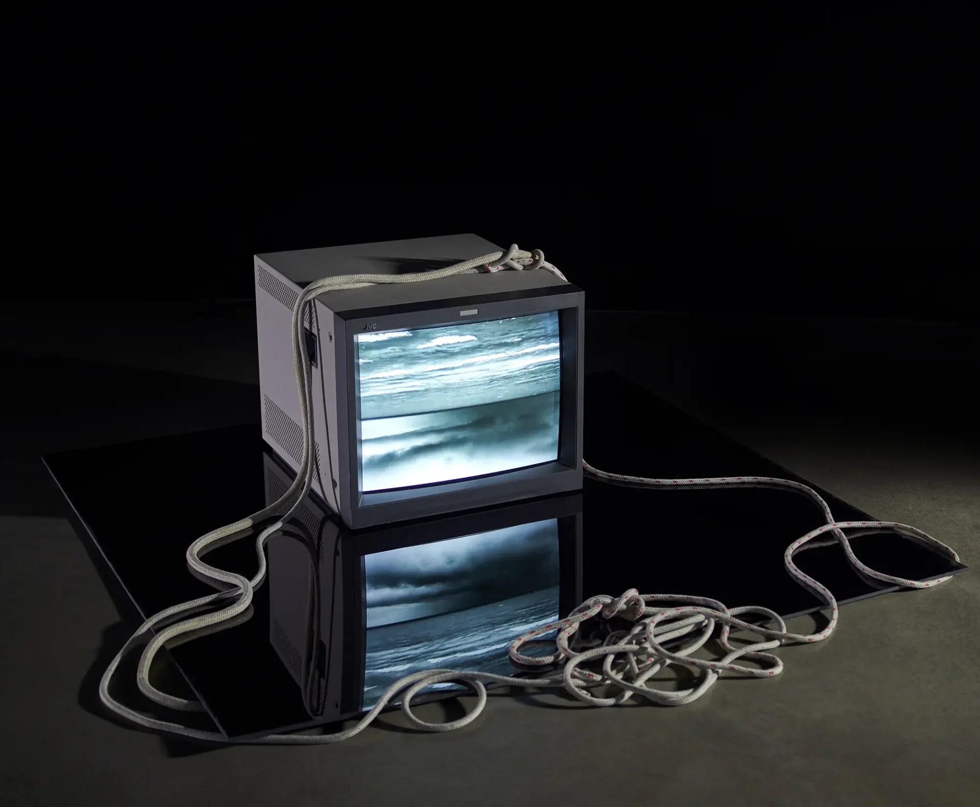 Documentation of video installation: analog CRT sitting on black acrylic for video reflection with 2 sailing lines, loosely anchoring the TV.
