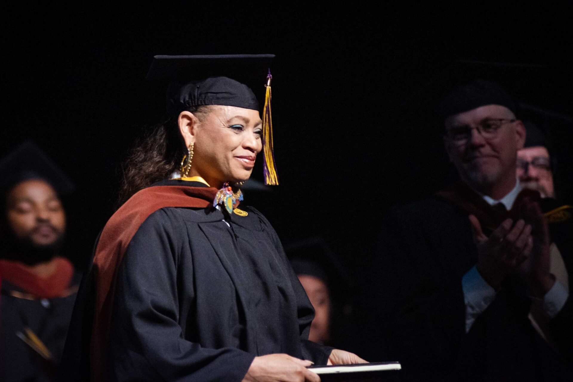 Sabrina Nelson smiles while seated in commencement regalia.