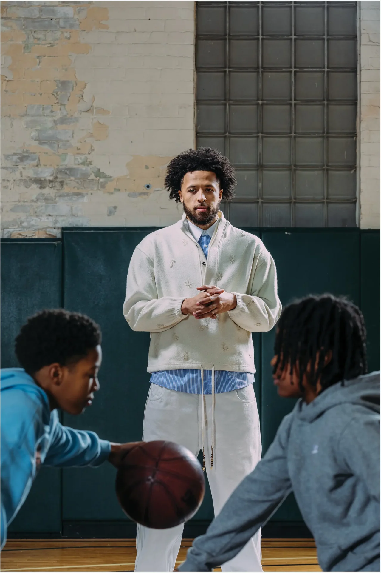 Environmental portrait of NBA star Cade Cunningham for GQ magazine with two children in the foreground playing basketball.