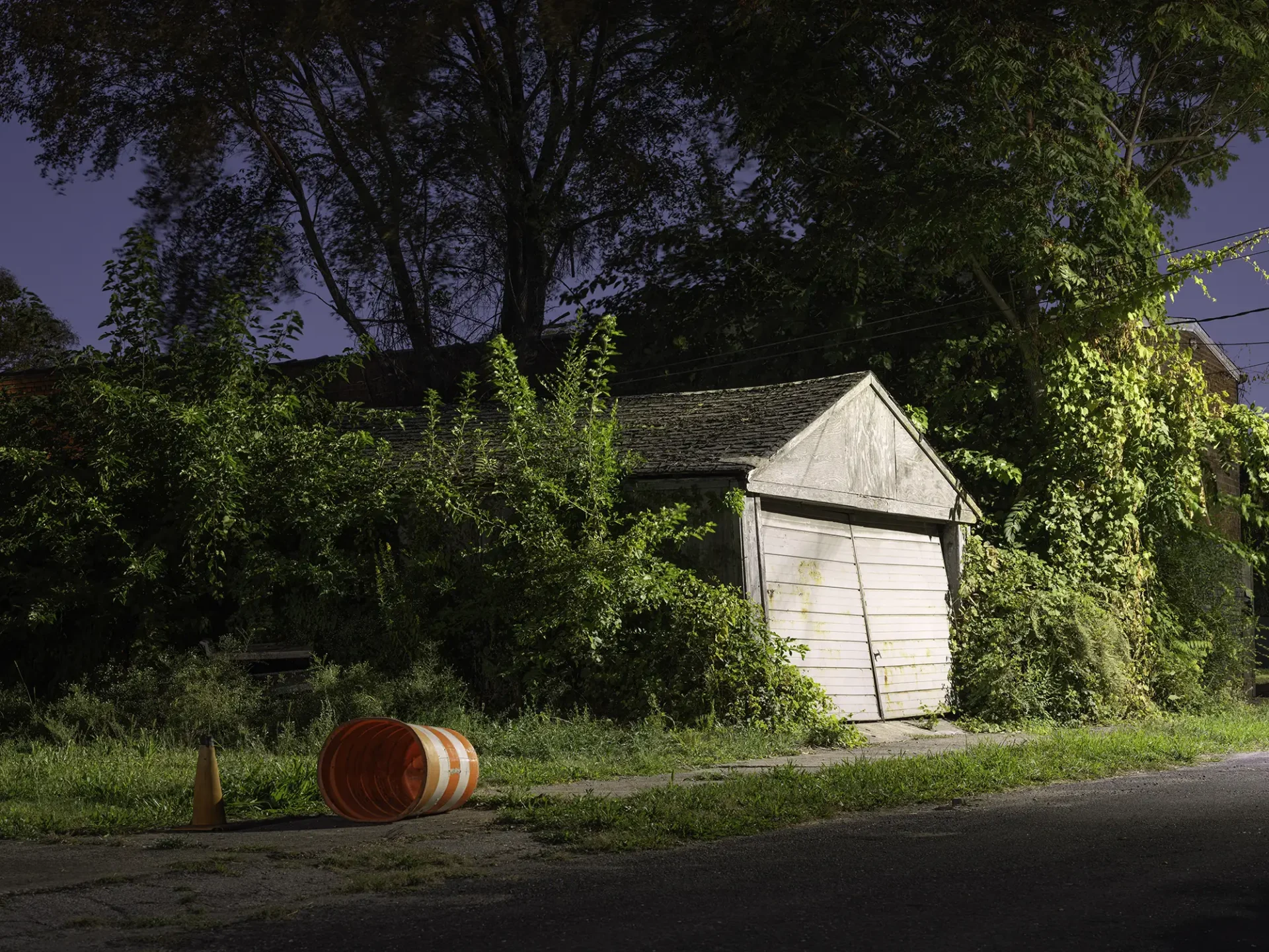 A dilapidated garage in a suburban alley at night.