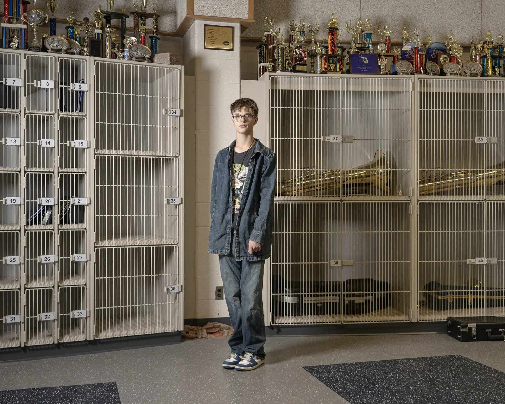 Environmental portrait of a tween-age boy in front of a wall of band lockers and trophies.
