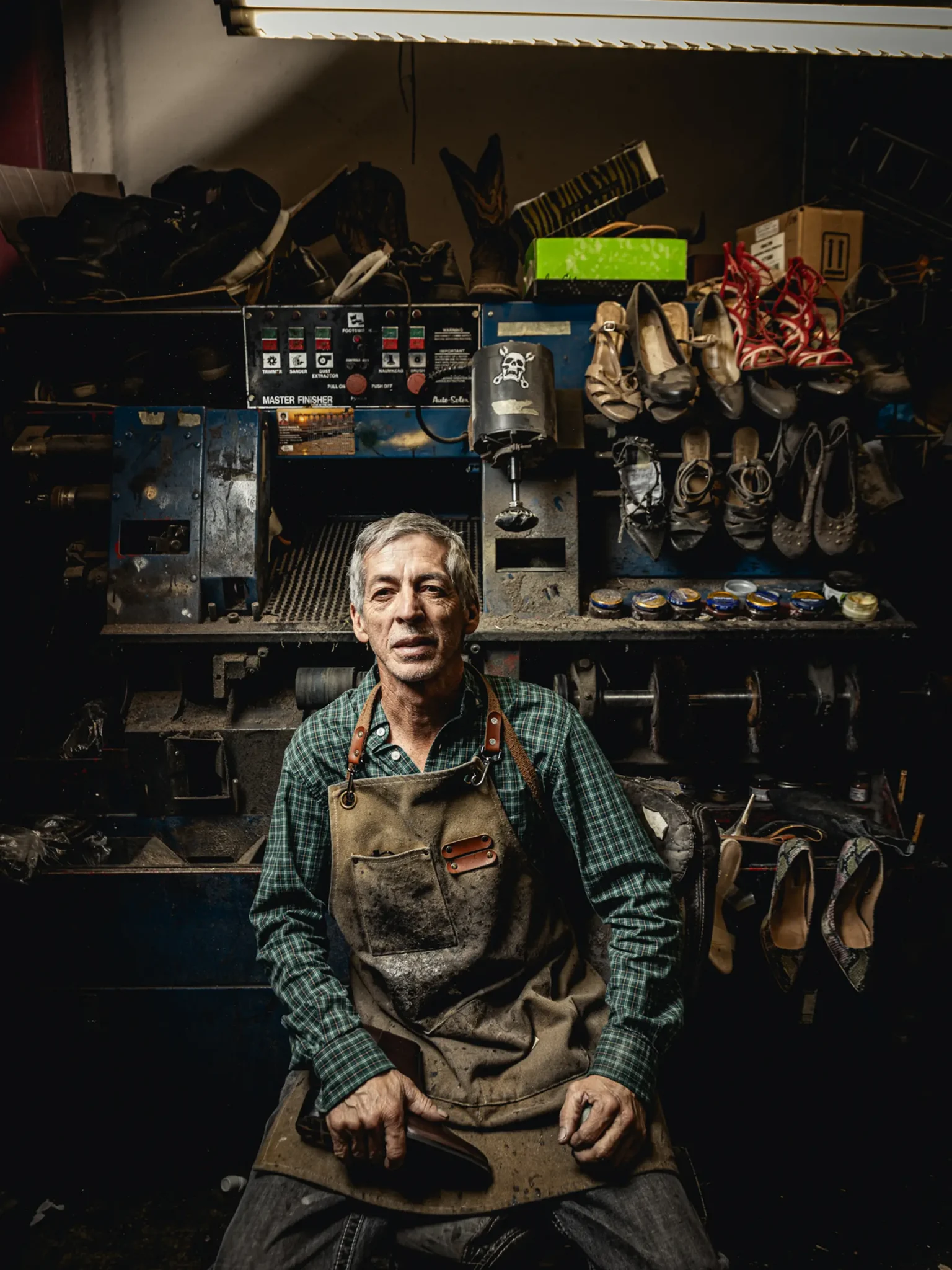 Environmental portrait of a cobbler sitting in his workshop.