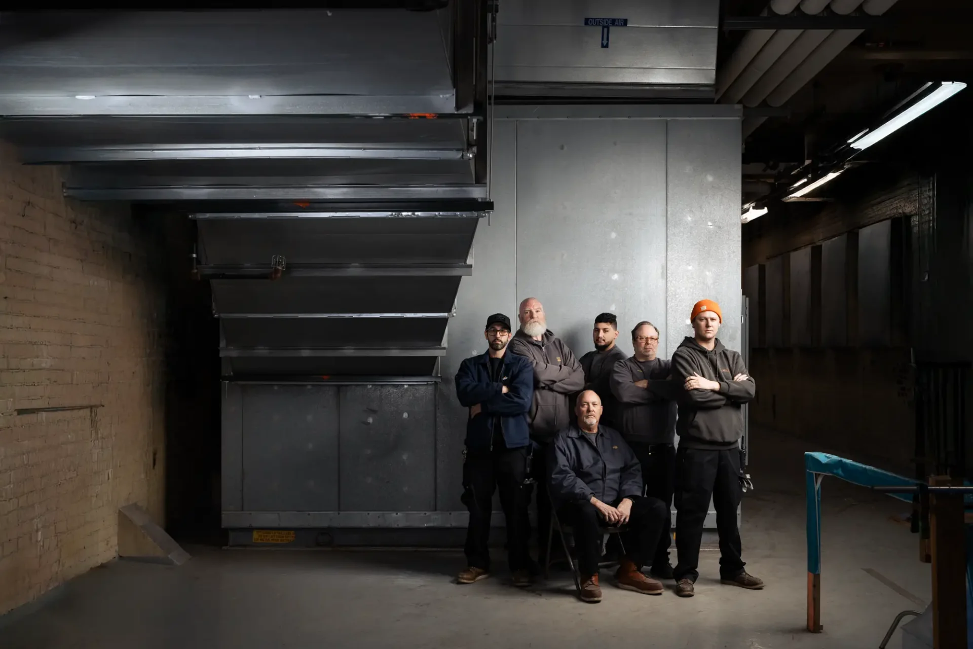 Environmental portrait of 6 members of the CCS Facilities team posing in front of the HVAC system.