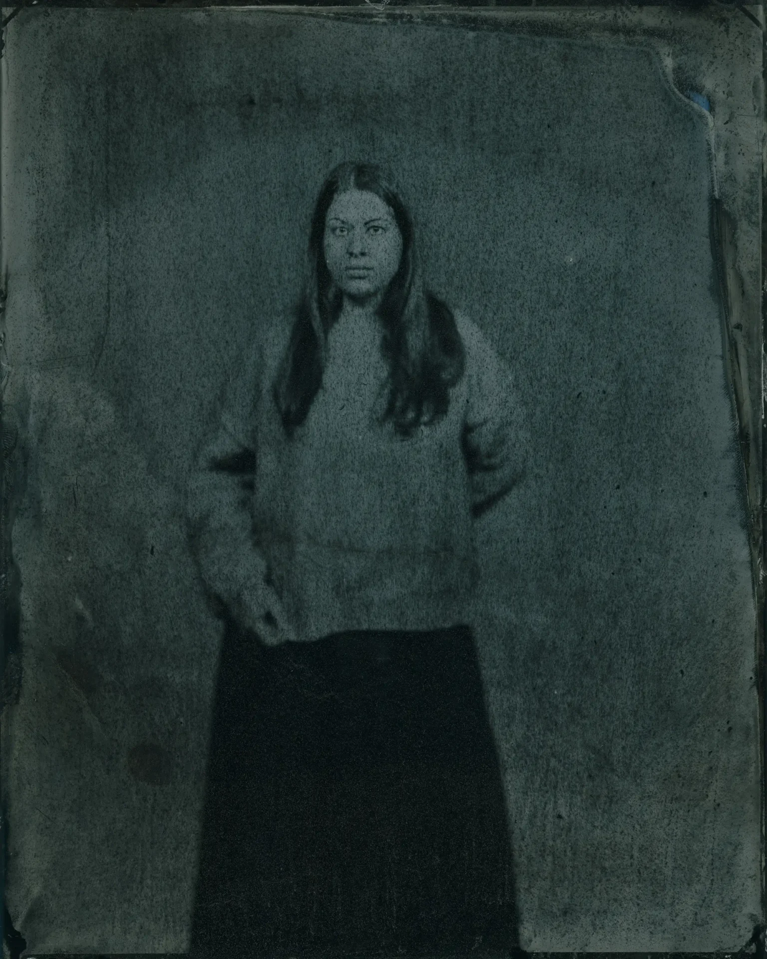 Tin type portrait of a woman wearing a sweater and long skirt.