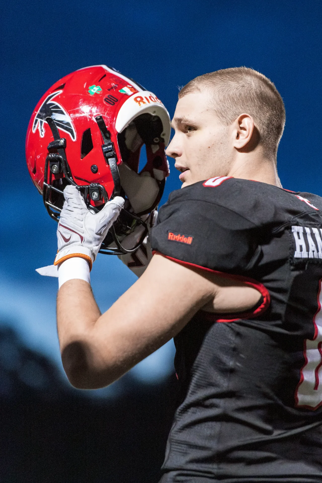 Photo of a football player putting on his helmet.