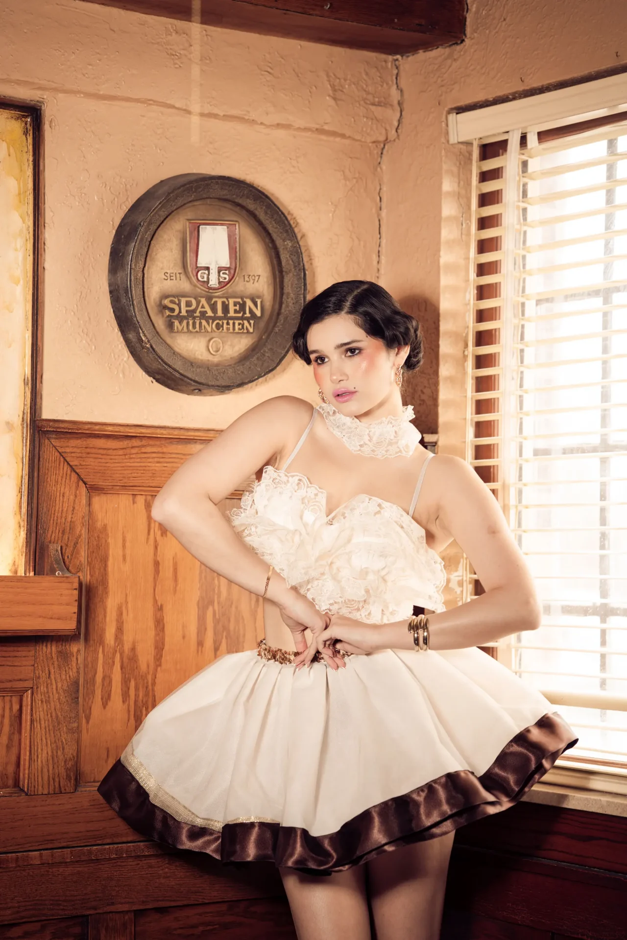Model wearing a lace bra top, necklace and a gathered woven textile skirt