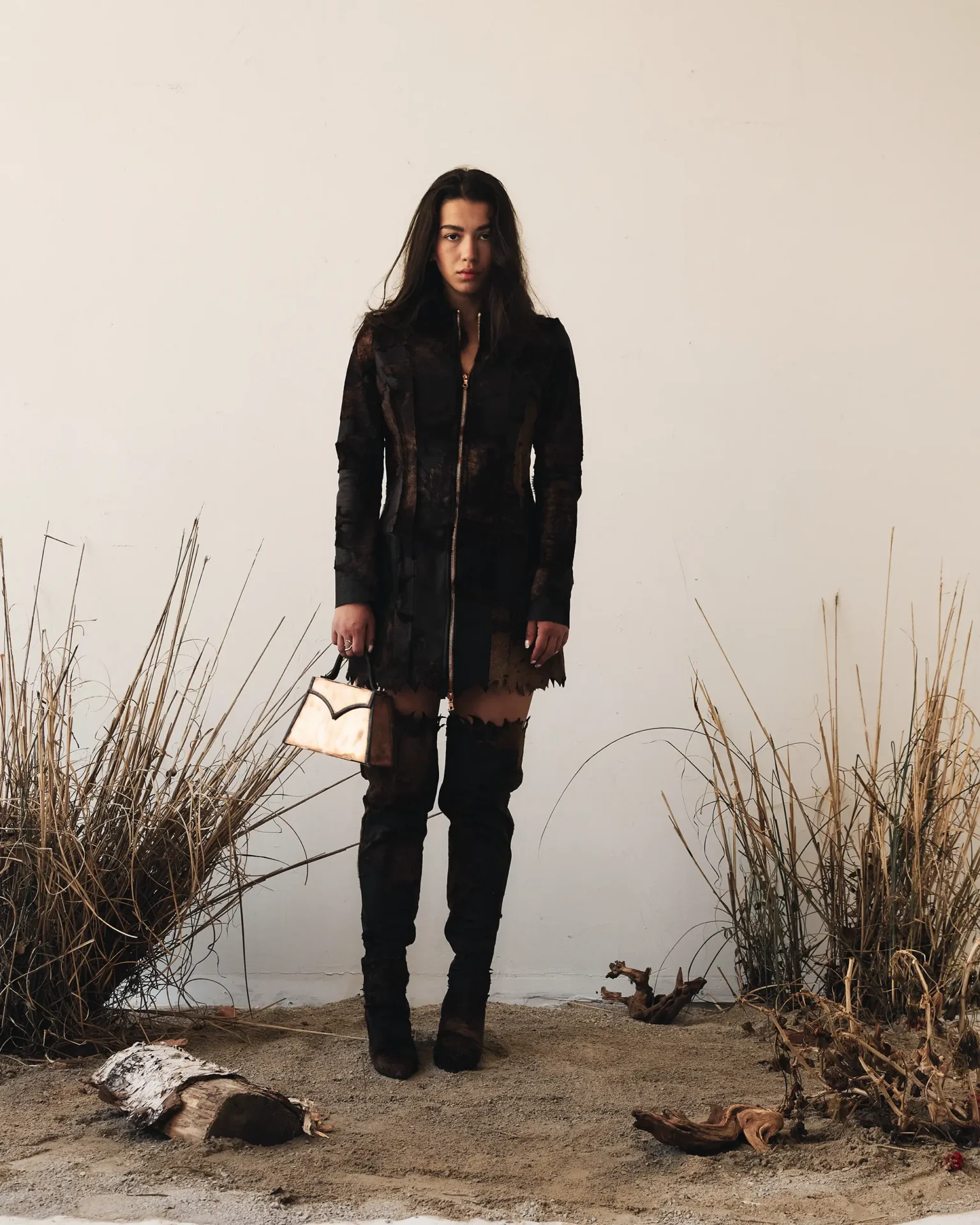 Model weather leather dress, leather thigh high boots and leather handbag