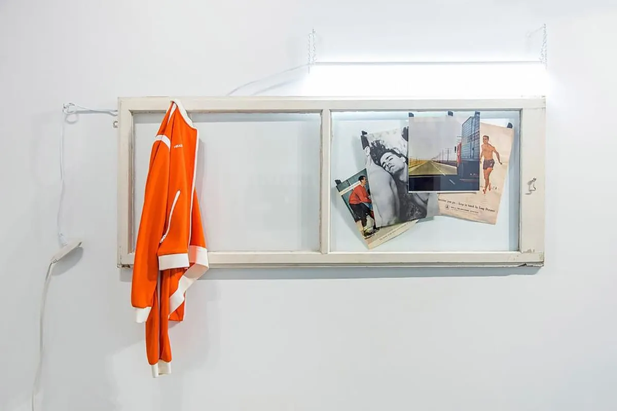 An isolated rectangular window pane, with a jacket hanging on one side and a series of photos and magazine pages on the other side