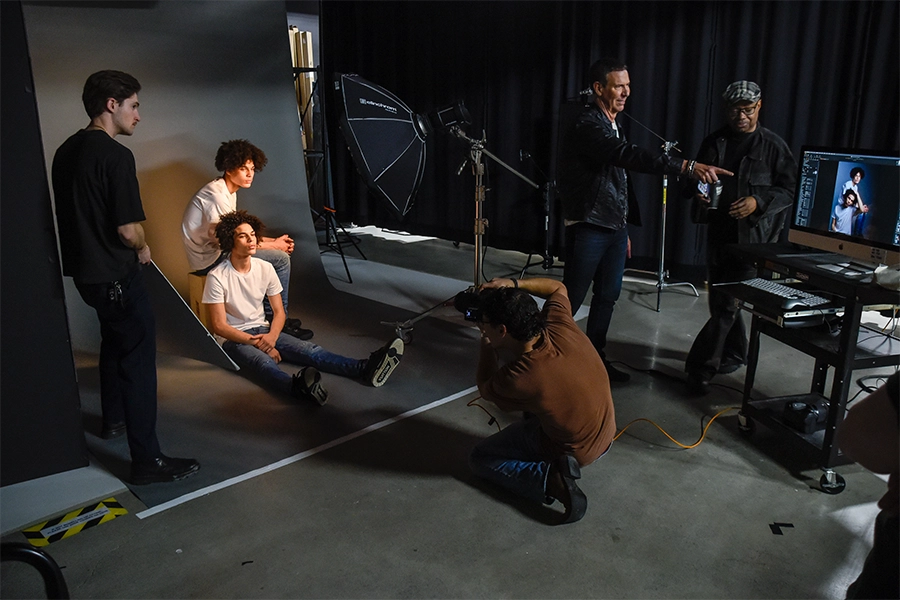 CCS students working in a darkened photography studio photographing models with professional equipment.