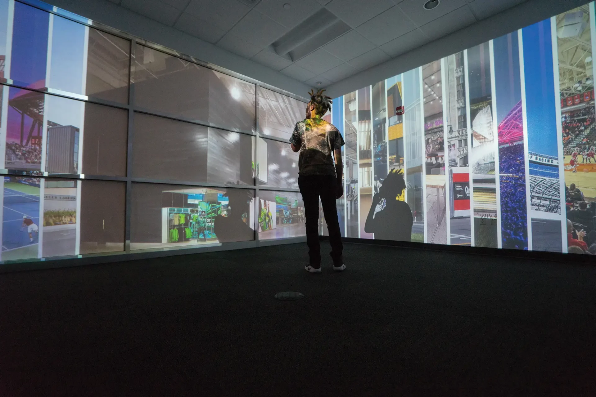 A person interacting with large-scale immersive display walls in a multimedia breakout room.