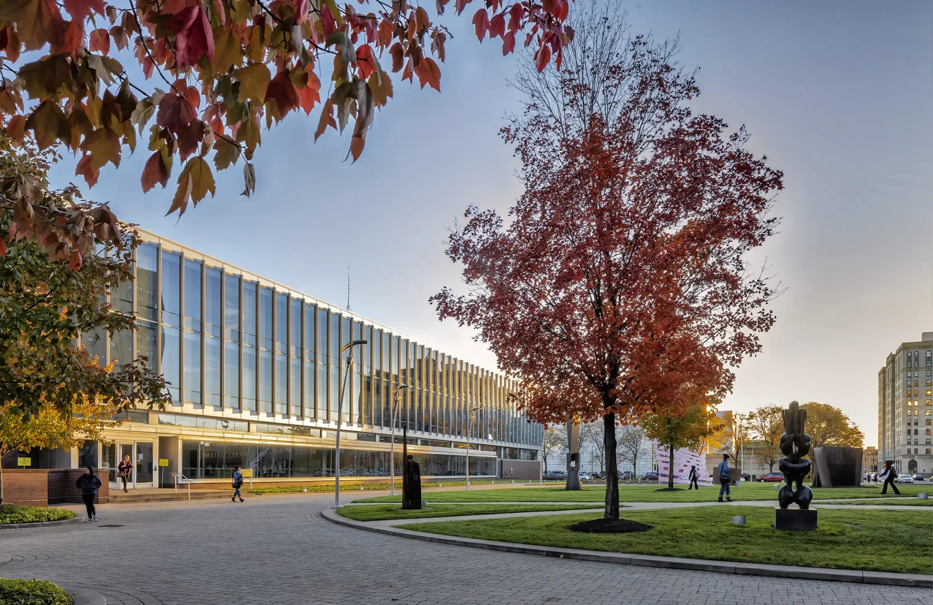 Students walking in front of the Ford Building at sunset at the Ford campus