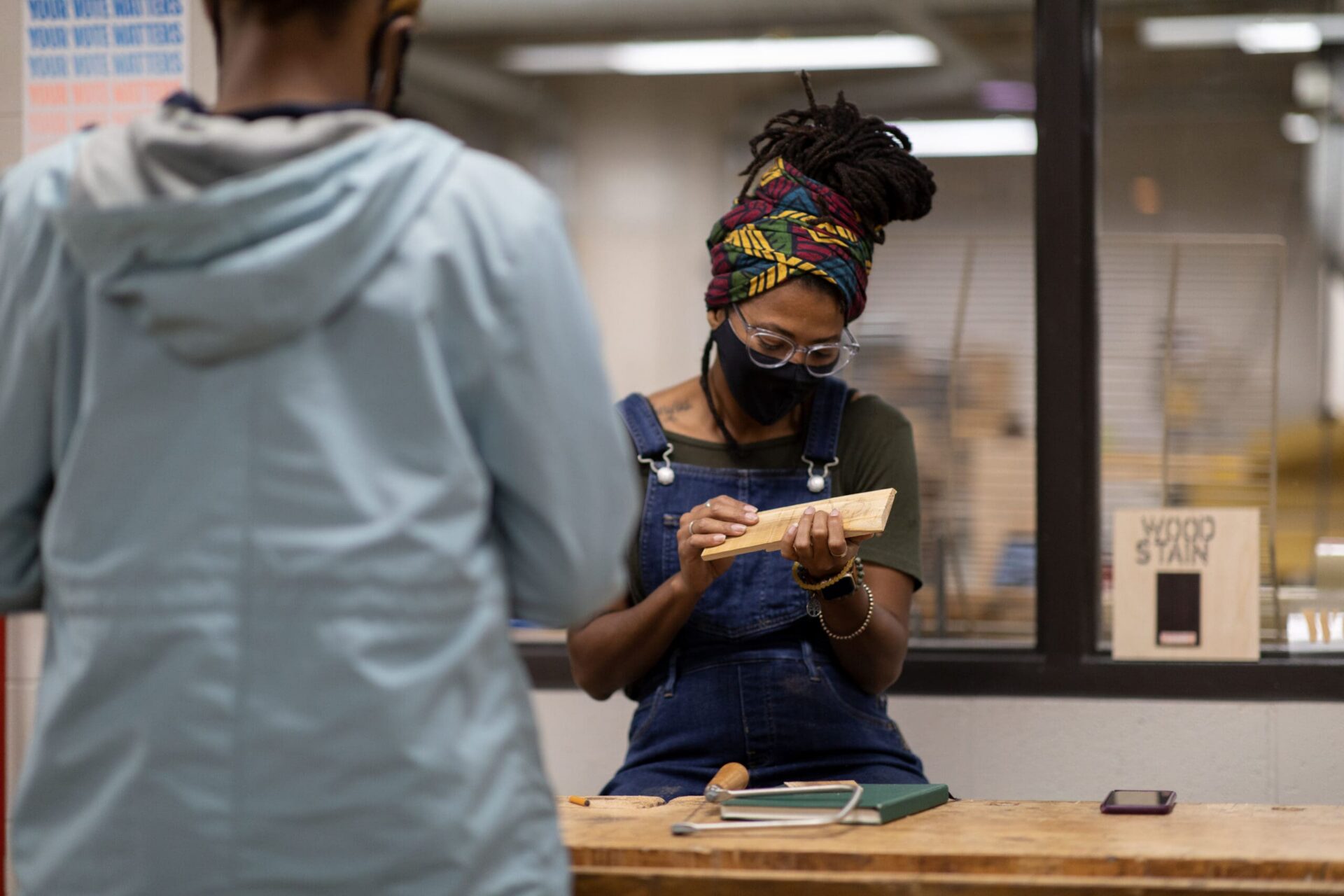 A student holding and examining a piece of wood