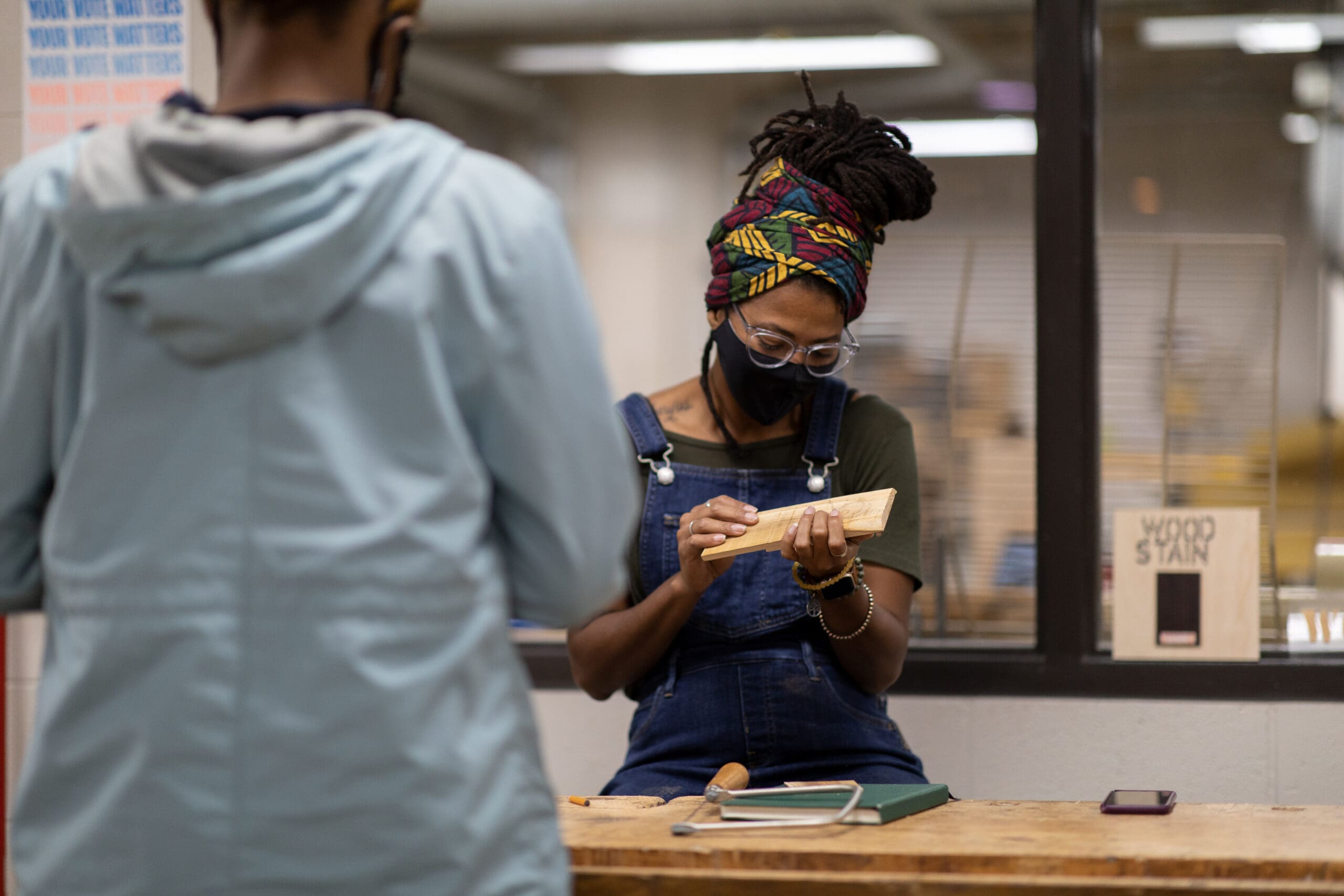 A student holding and examining a piece of wood