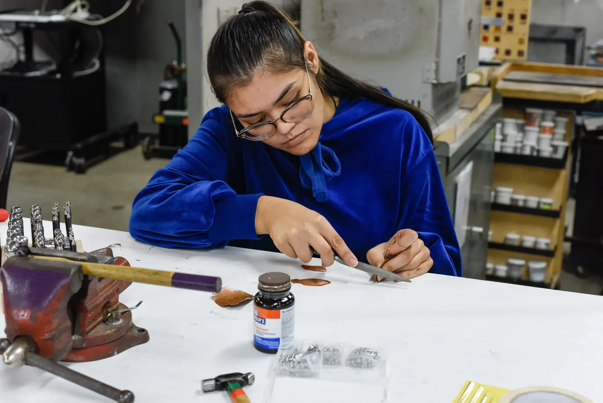 A student filing down a piece of jewelry at a table