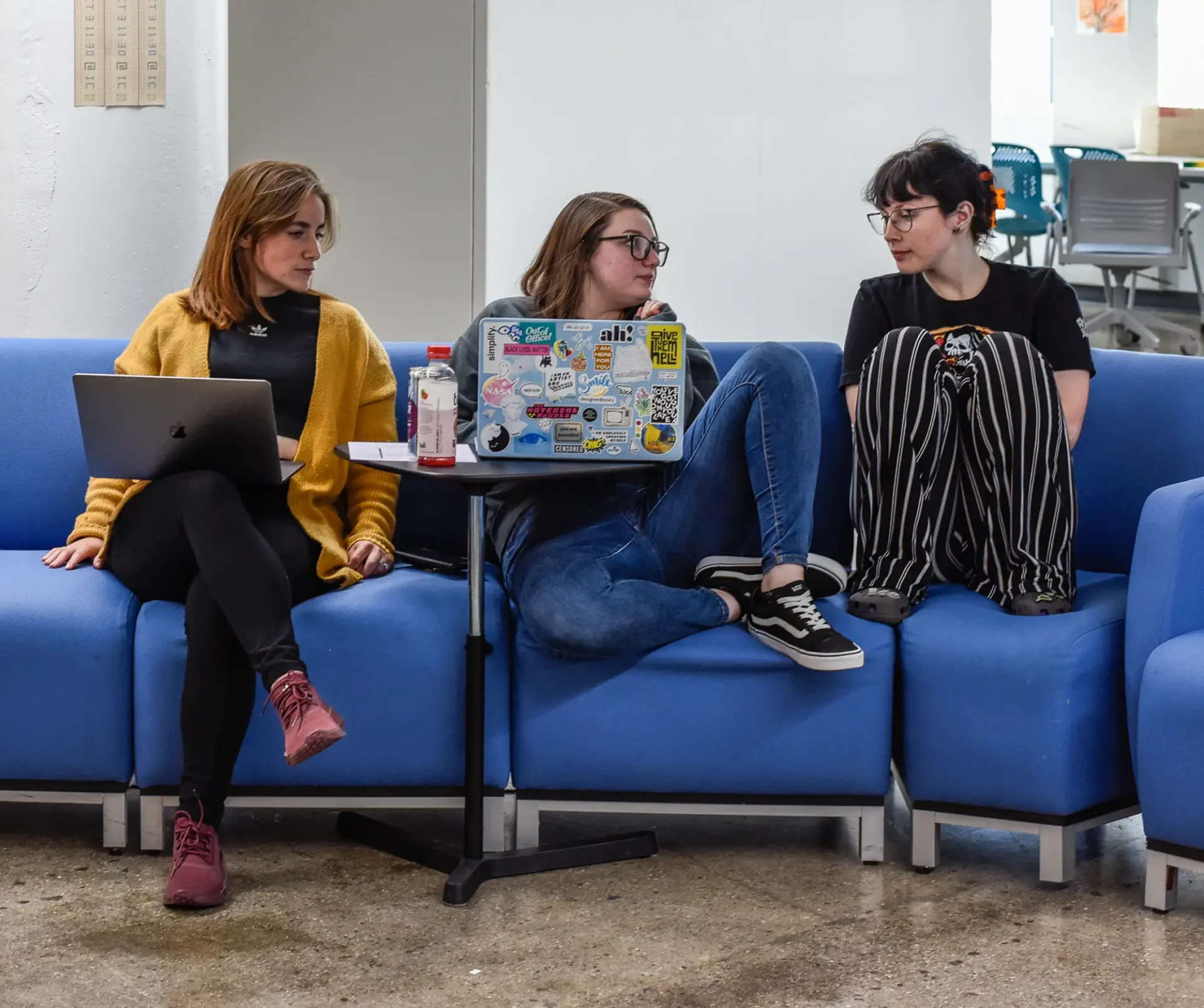 Three students sitting on a couch around a laptop