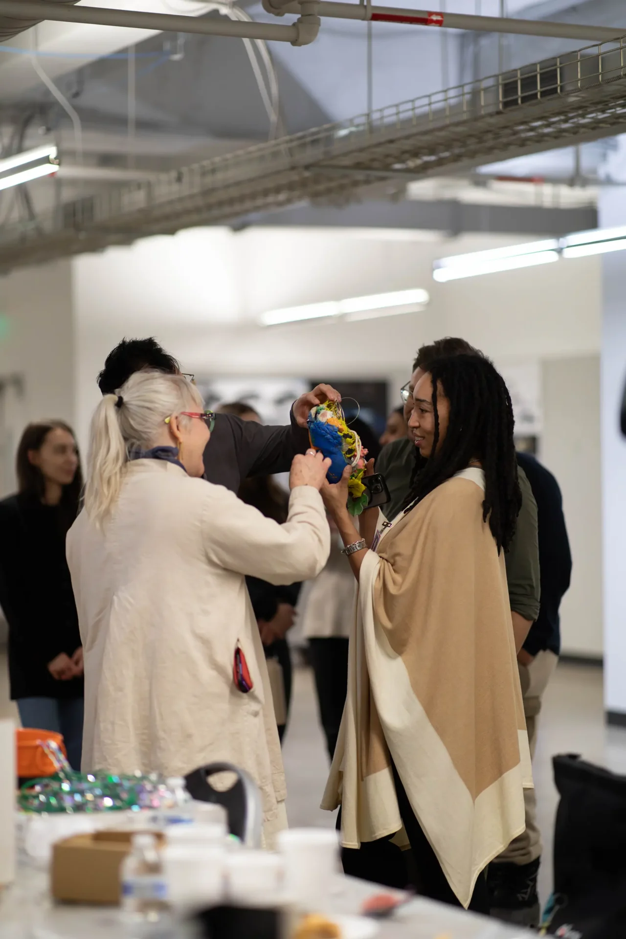 A group of students smiling and examining a piece of artwork one is holding for all to see