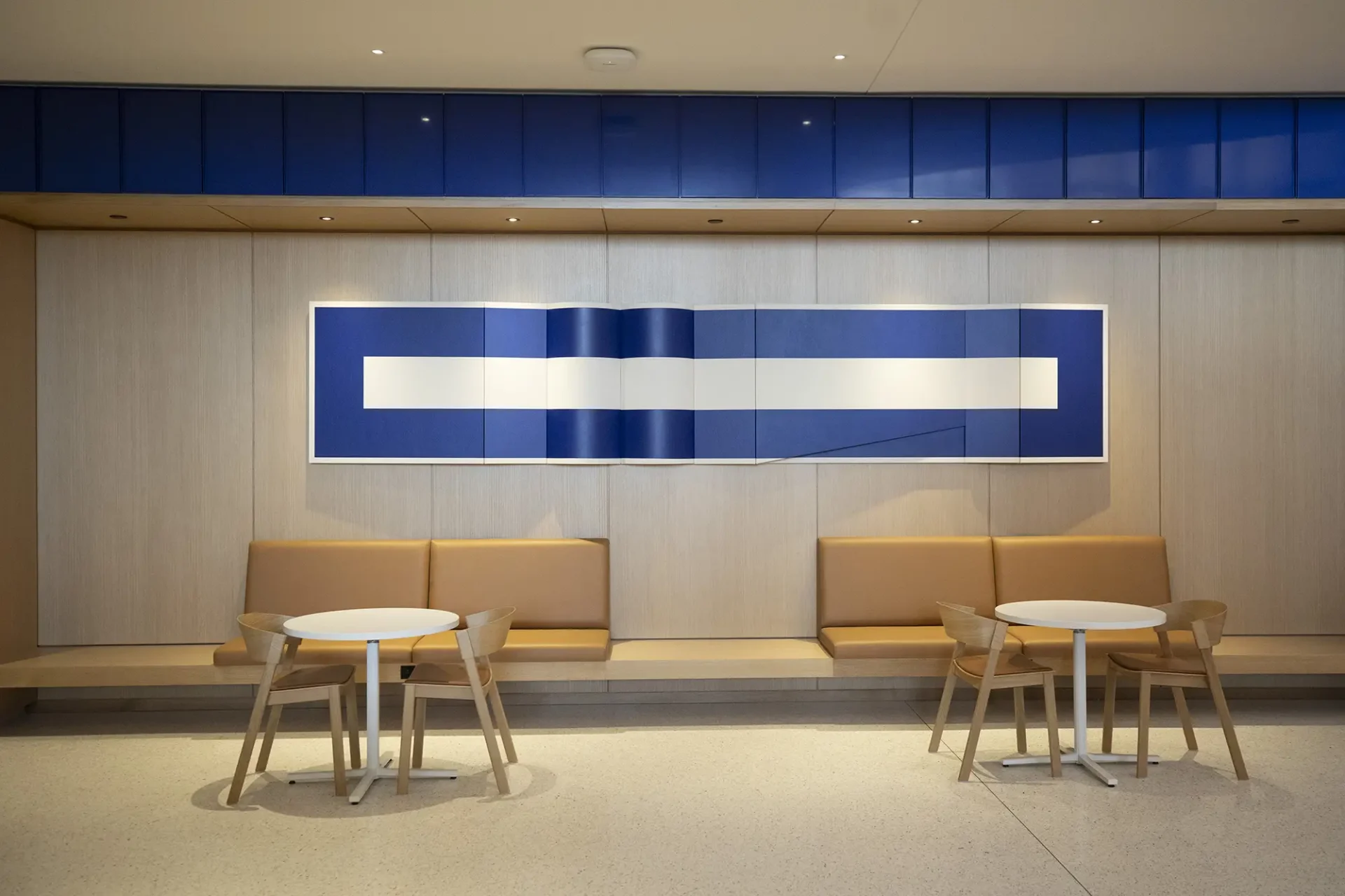 An image of a lobby featuring multiple seating areas a large piece of wall art behind