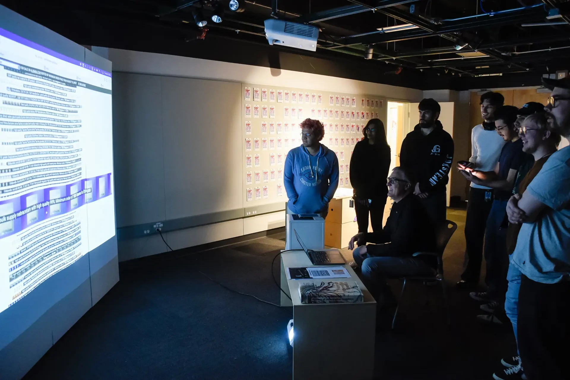 Professor works with students reviewing an interactive design project.